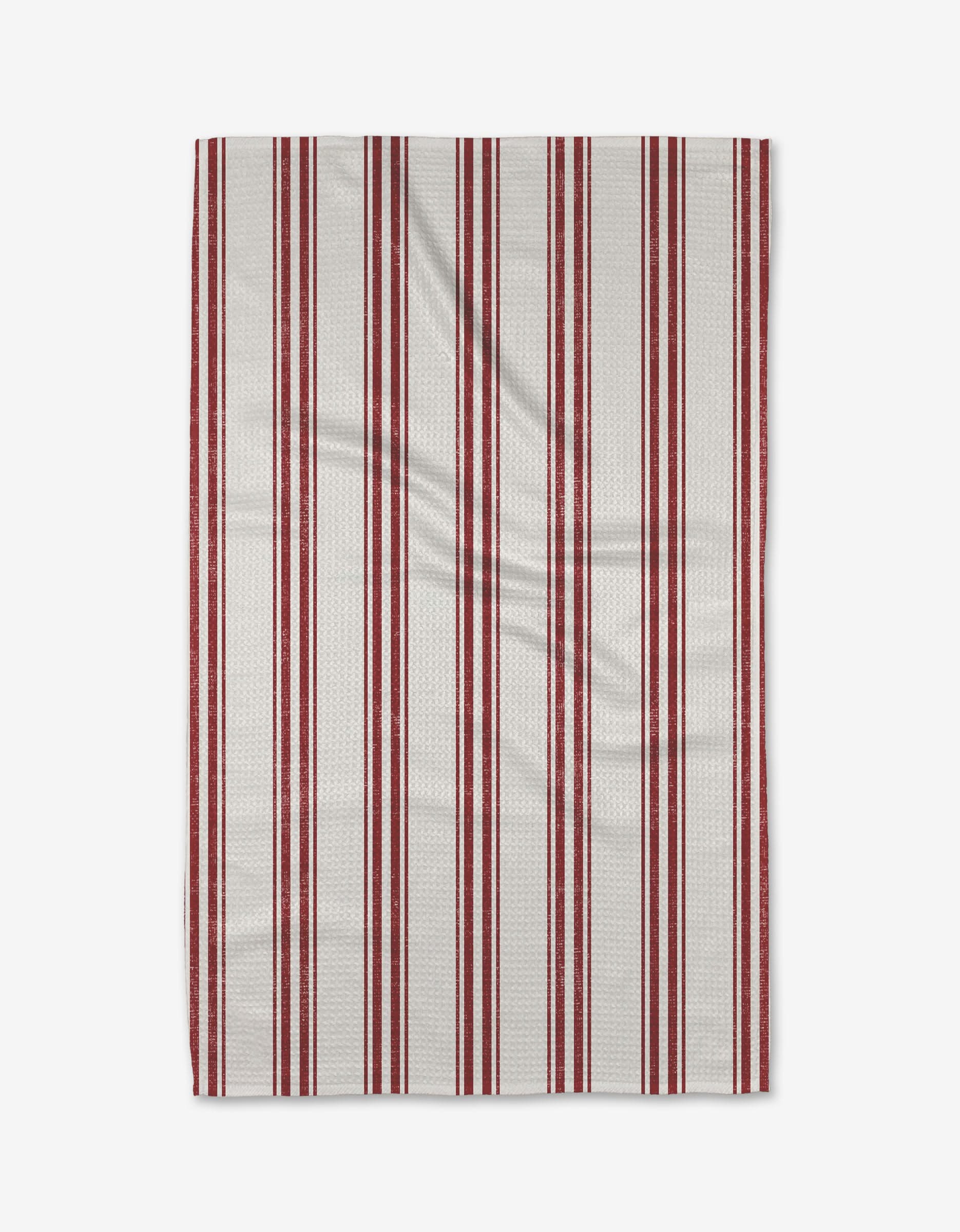 The Peppermint Present tea towel by Becki Owens features evenly spaced vertical red stripes of varying thickness on a white background, with the Geoweave fabric showing slight creases and texture.