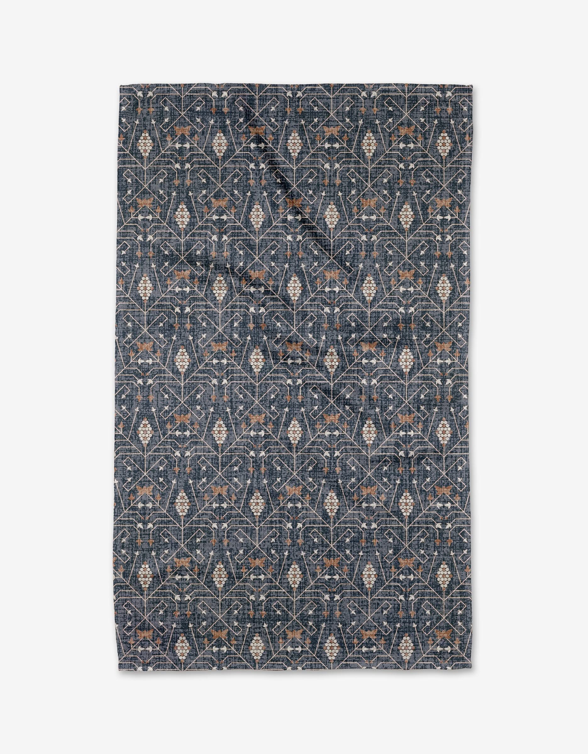 The Rulon Blue quilt by Becki Owens features an intricate floral and vine pattern in beige and light brown on dark blue, crafted from recycled materials, shown flat on a white background.