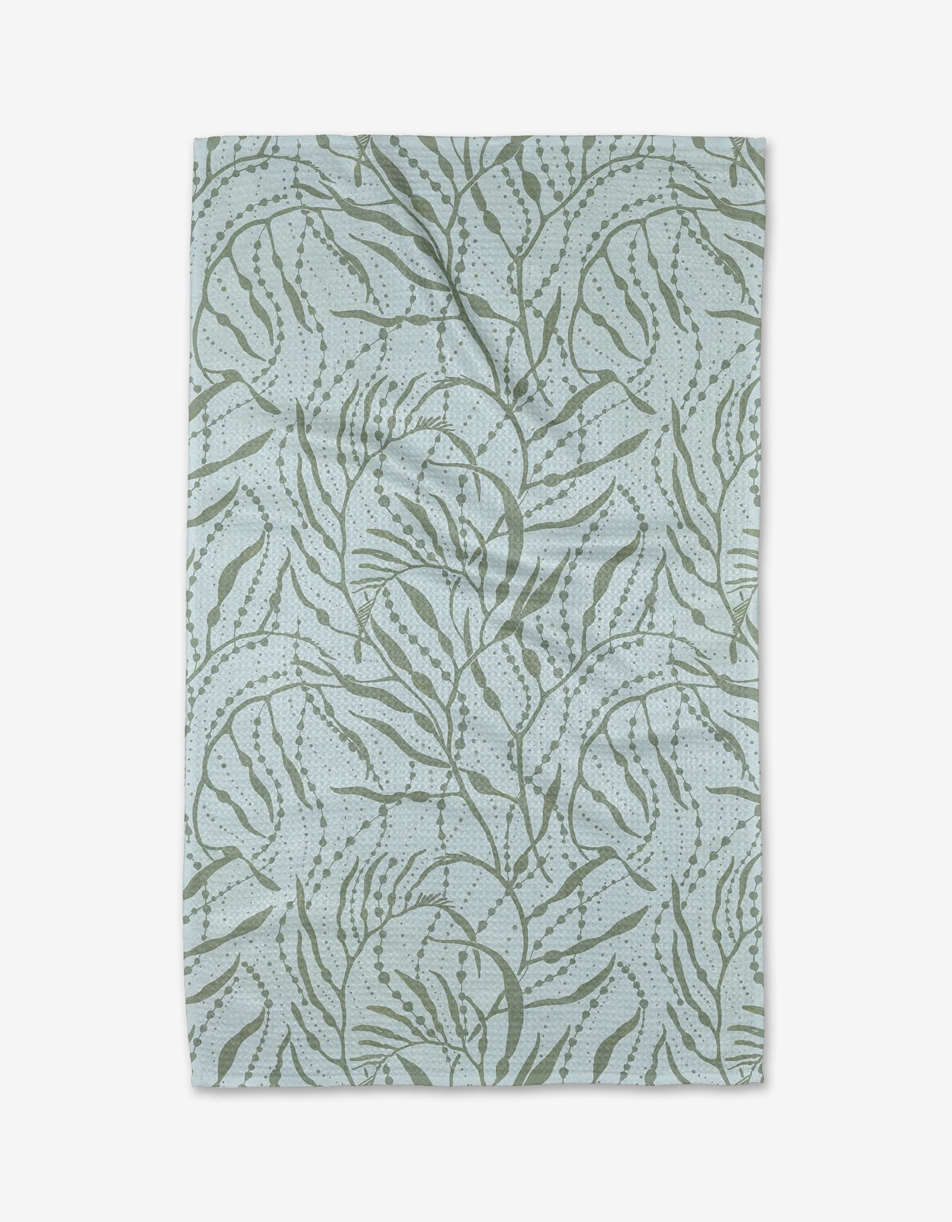 The Sea Forest Tea Towel by Katie OShea is a rectangular, light blue towel with an abstract green botanical pattern on ultra-absorbent Geoweave fabric. The slightly textured cloth displays visible folds and creases.