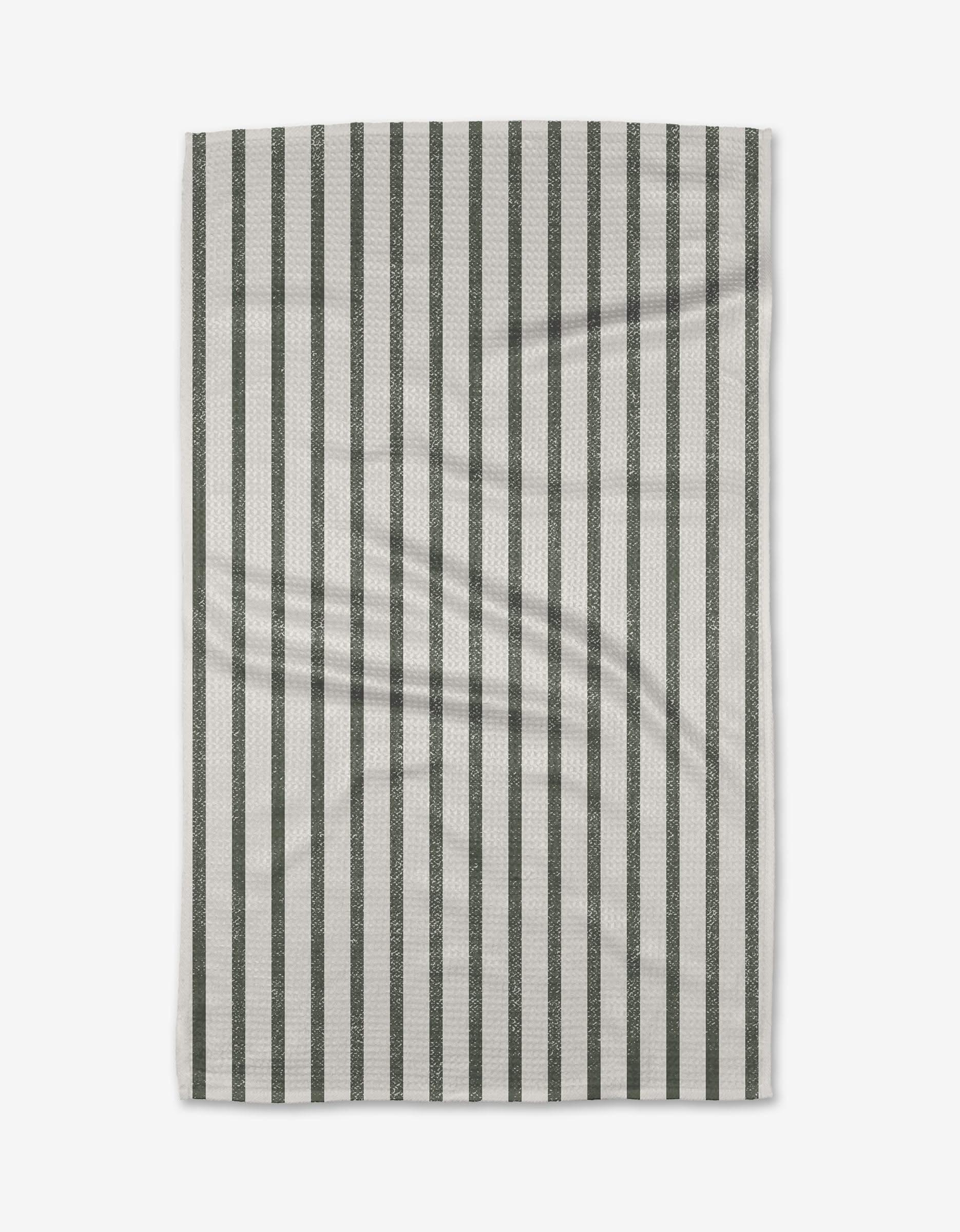 The Spearmint tea towel by Becki Owens is rectangular, white, and made from recycled Geoweave fabric, with evenly spaced vertical dark green stripes and subtle folds visible when laid flat.