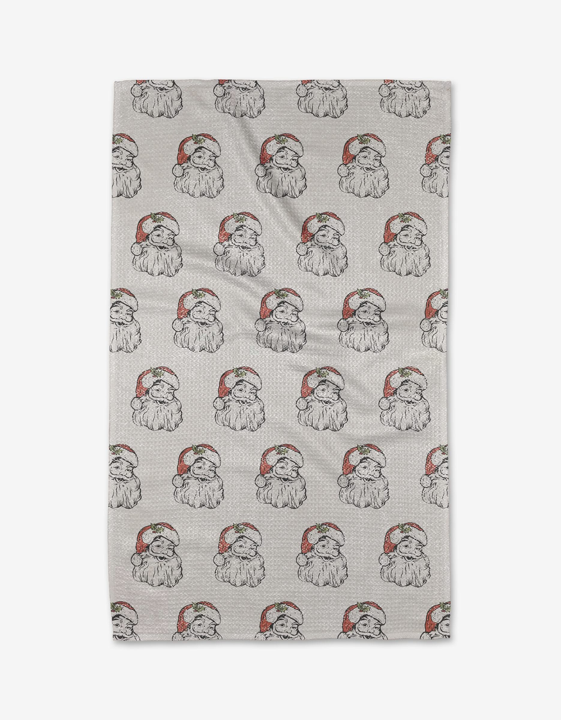 The Becki Owens St. Nick kitchen towel is light gray and ultra-absorbent, decorated with a festive pattern of dogs in red and white Santa hats.