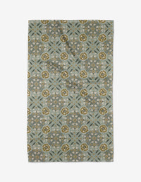 The Summit Check tea towel by Ash Cascade features a rectangular design with intricate floral and geometric patterns in olive green, gold, and gray on a muted blue-gray background, bringing charm and absorbency to any kitchen.