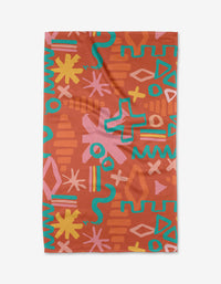 The Superstar Tea Towel by Sareka Unique is made from Geoweave fabric and showcases a bold, colorful abstract pattern—yellow, pink, blue, and orange zigzags, stars, waves, and crosses—on a reddish-brown background.