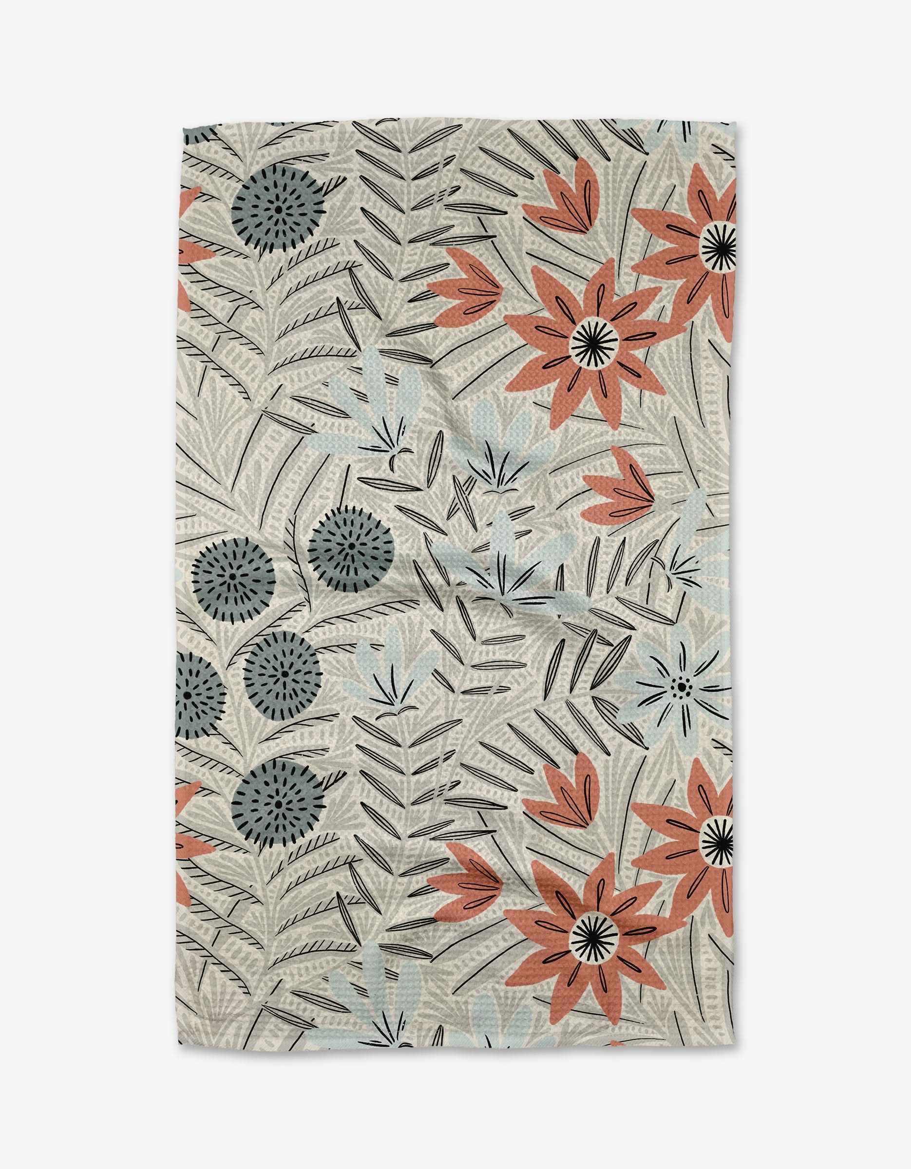 The Teagan Cream tea towel by Amy MacCready features a floral pattern with large orange, blue, and black flowers and gray leaves on a light beige background. Made from recycled materials, the fabric has a slightly wrinkled look.