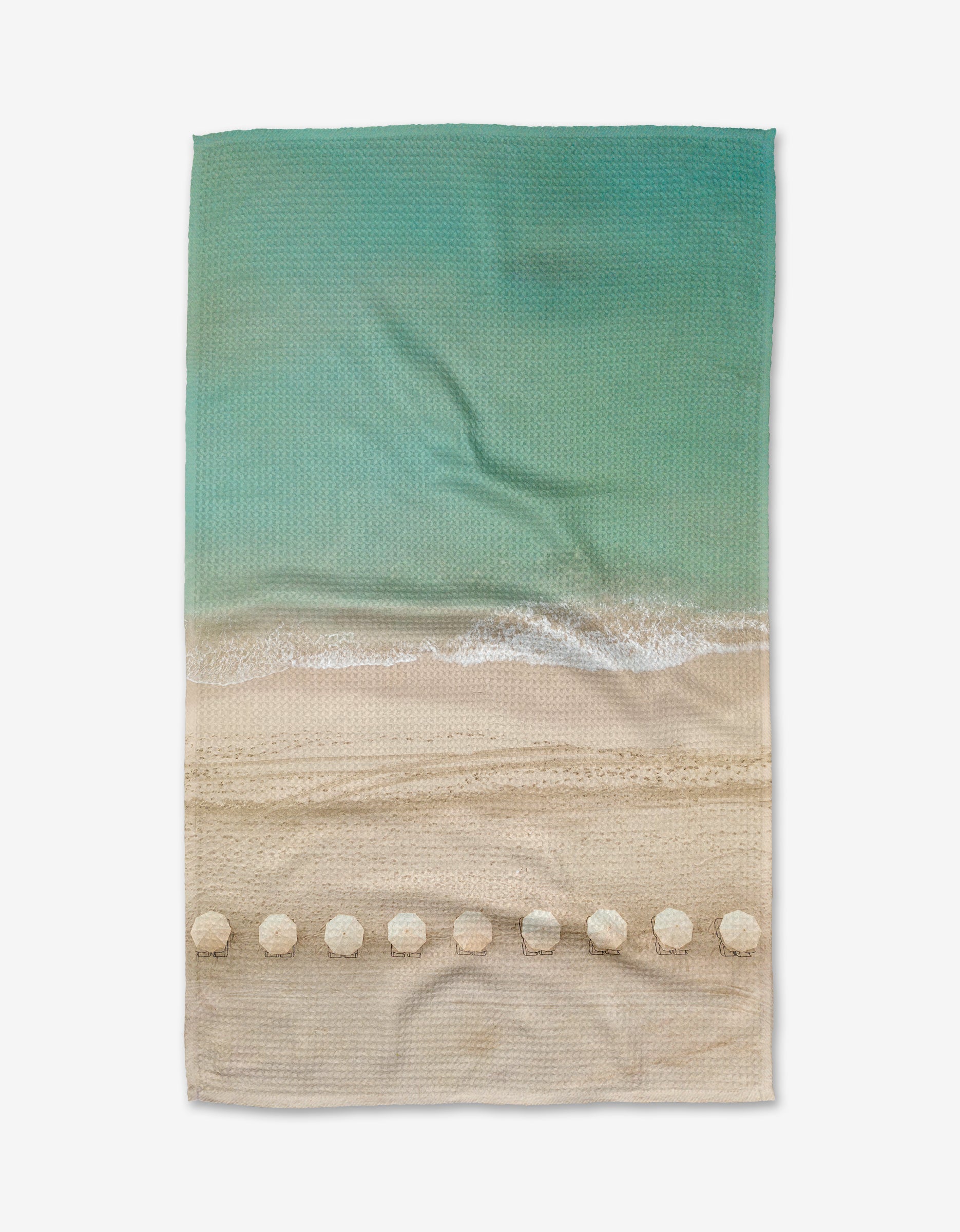 The Kait Hanson Waikiki towel is a rectangular beach towel made from Geoweave™ fabric, featuring a printed design of waves, white foam, and seashell shapes along the edge. The towel is shown laid flat on a white background.