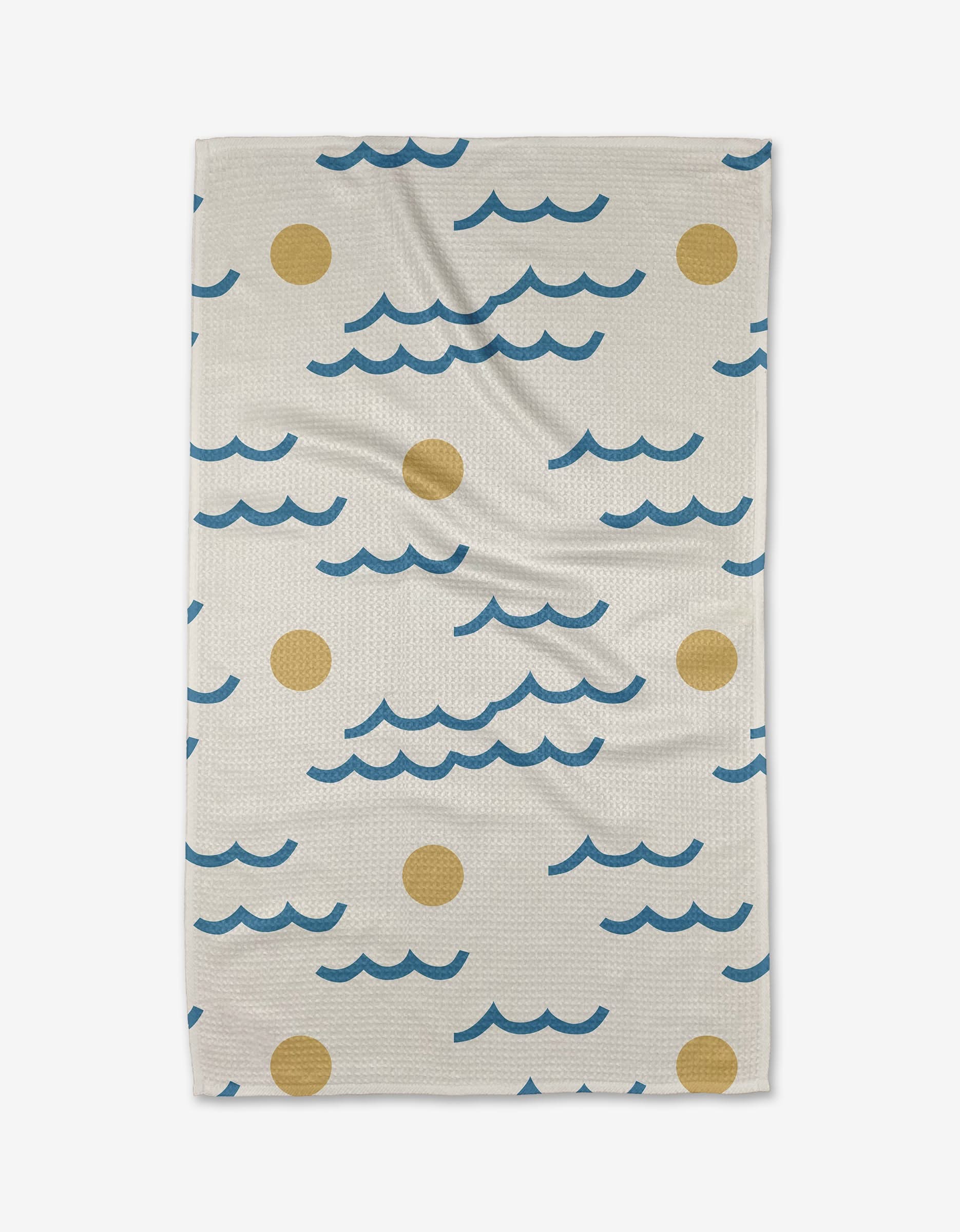 The Wavy Day Tea Towel by Elizabeth Edwards, in beige and made from recycled materials, showcases blue wavy lines and yellow circles reminiscent of waves and suns, displayed flat on a white background.