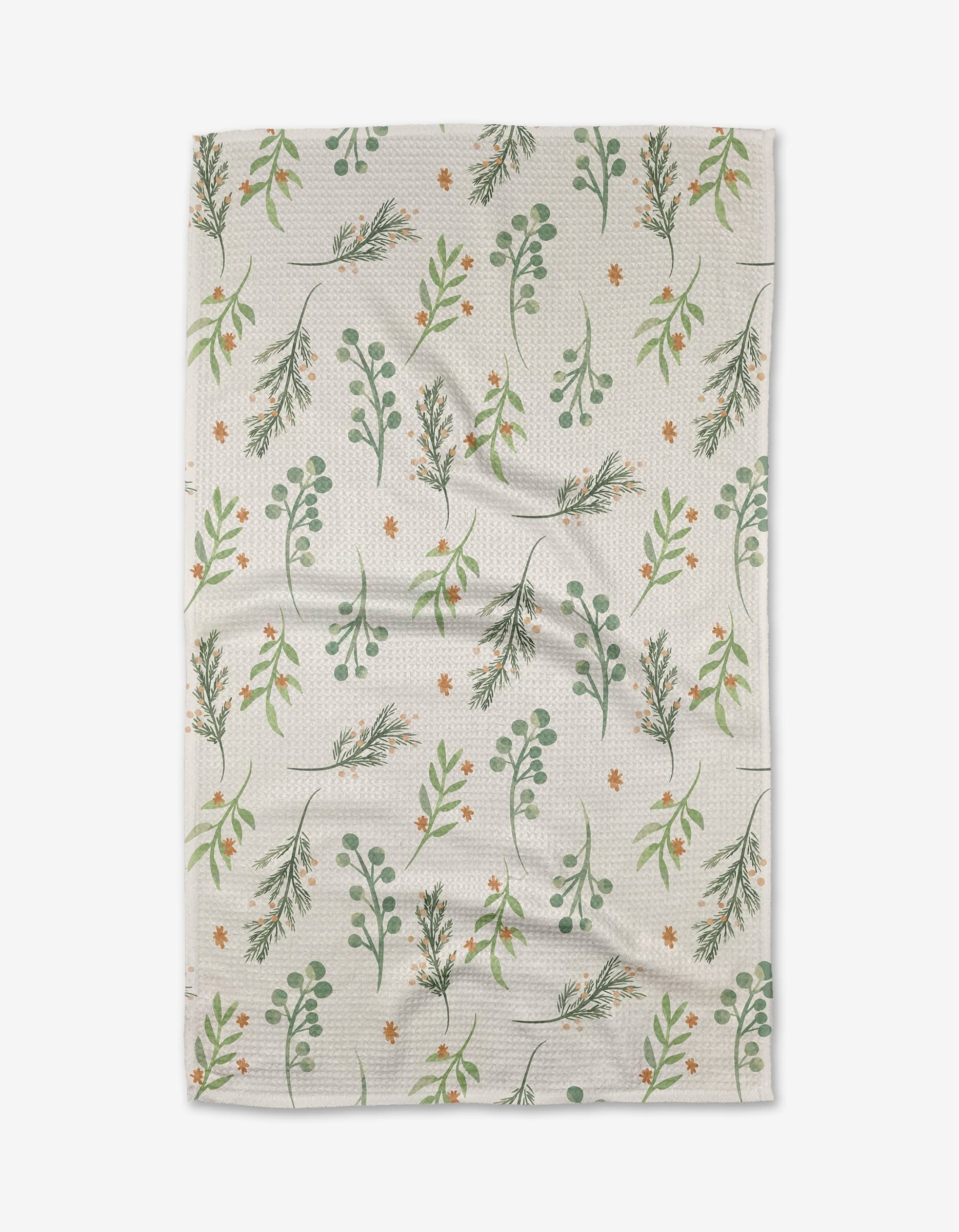 Winter Greens by Janna Sue Design is a white textured kitchen tea towel with green leaves, branches, and orange flowers in a scattered design—crafted from recycled materials for eco-friendly style.