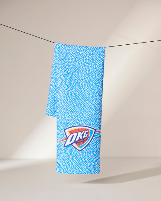 A blue textured towel with the Oklahoma City Thunder (OKC) logo hangs on a black clothesline against a neutral background with soft lighting.