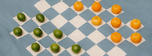 A split image: on the left, a checkerboard with limes and tangerines as pieces; on the right, three children play a board game on a blanket at the beach.
