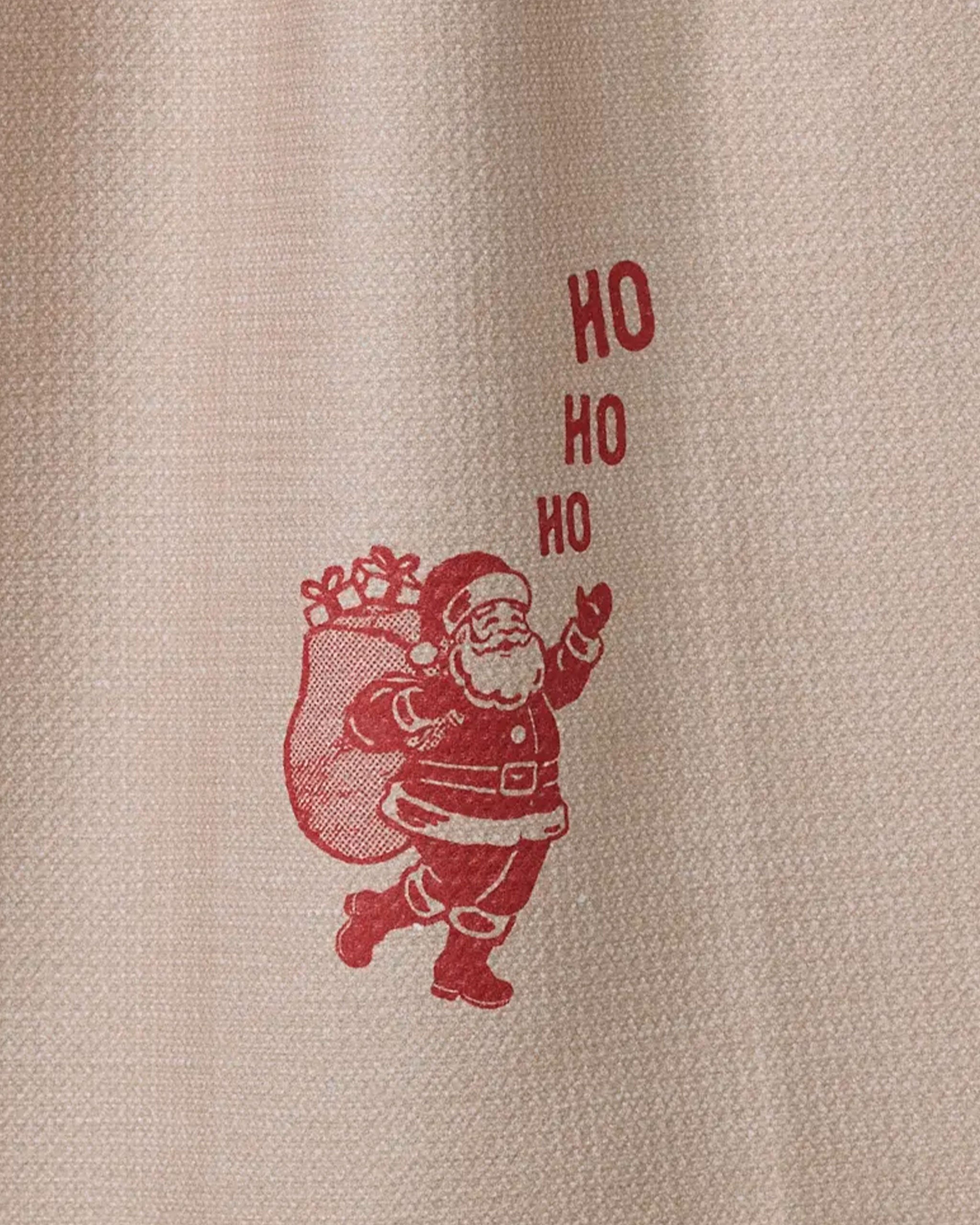 The Geometry "Clausco" dish towel features a red Santa Claus illustration with "HO HO HO" above him, printed on an absorbent, textured beige fabric.