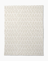 The Geometry Abstract Squiggles Butter Blanket features a cream base with repeating wavy brown lines, making this soft throw perfect for cozying up in style.