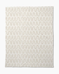 The Geometry Abstract Squiggles Butter Blanket features a cream base with repeating wavy brown lines, making this soft throw perfect for cozying up in style.