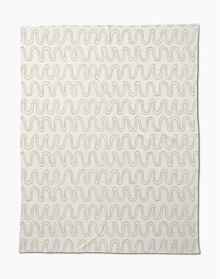 The Geometry Abstract Squiggles Butter Blanket features a cream base with repeating wavy brown lines, making this soft throw perfect for cozying up in style.