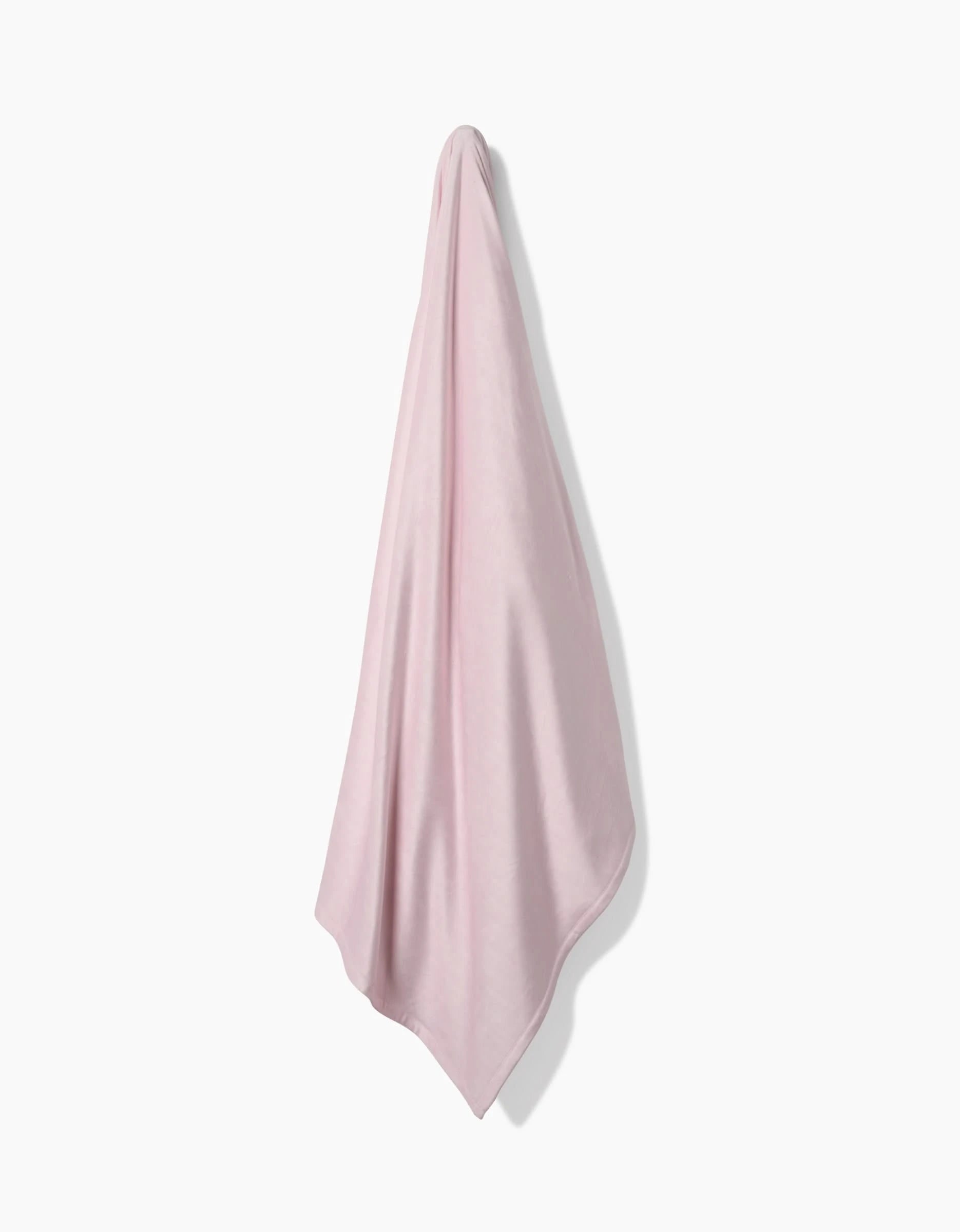 A Berry Shortcake towel by GEOMETRY, made from post-consumer recycled materials, hangs on a white wall, draped smoothly with gentle folds that create soft shadows.