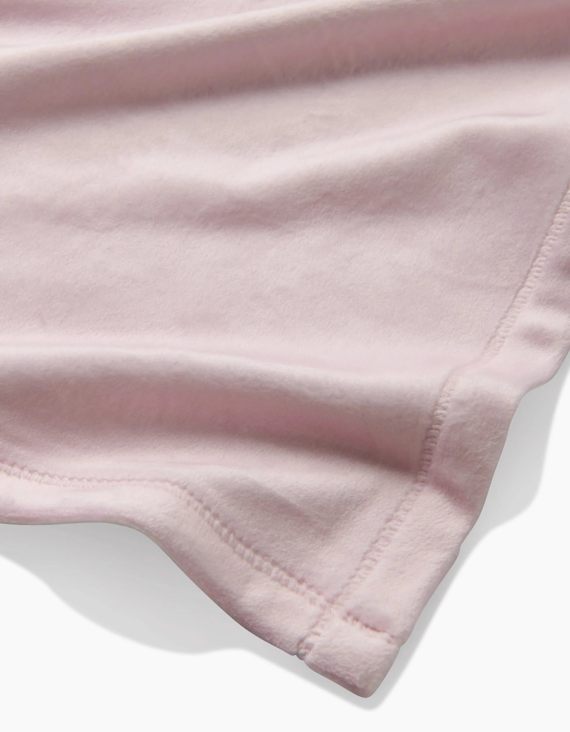 A close-up of GEOMETRYs Berry Shortcake fabric reveals light pink tones, delicate stitching, and gentle folds—showcasing its silky softness for cozy comfort.