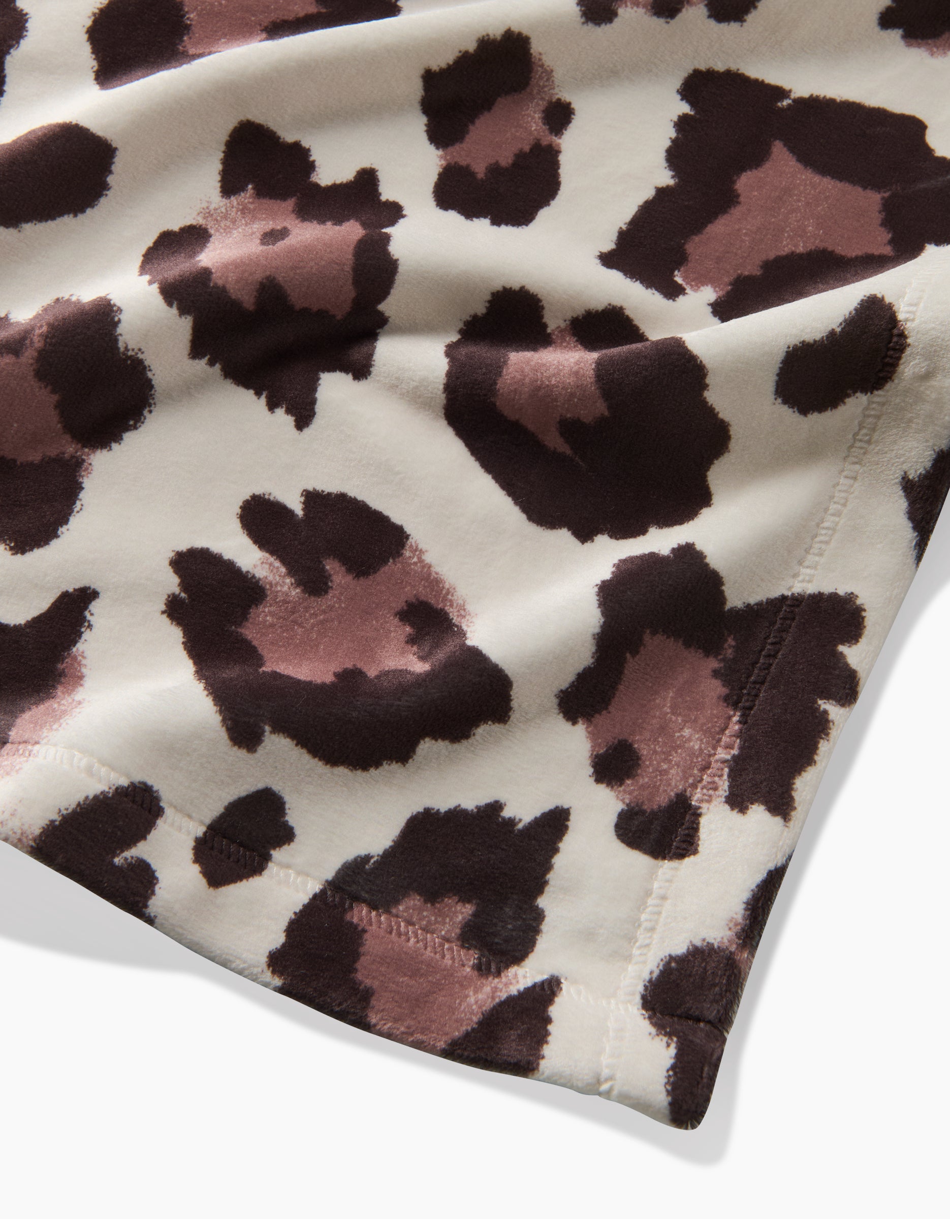 A close-up of Geometry’s Cheetah fabric shows detailed stitching on the edge with an animal print—irregular brown and black spots on a cream recycled material.