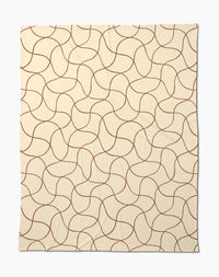 The Clarity throw by Geometry features a beige butter hue with abstract, wavy brown lines—a soft, cozy blanket perfect for relaxing evenings.