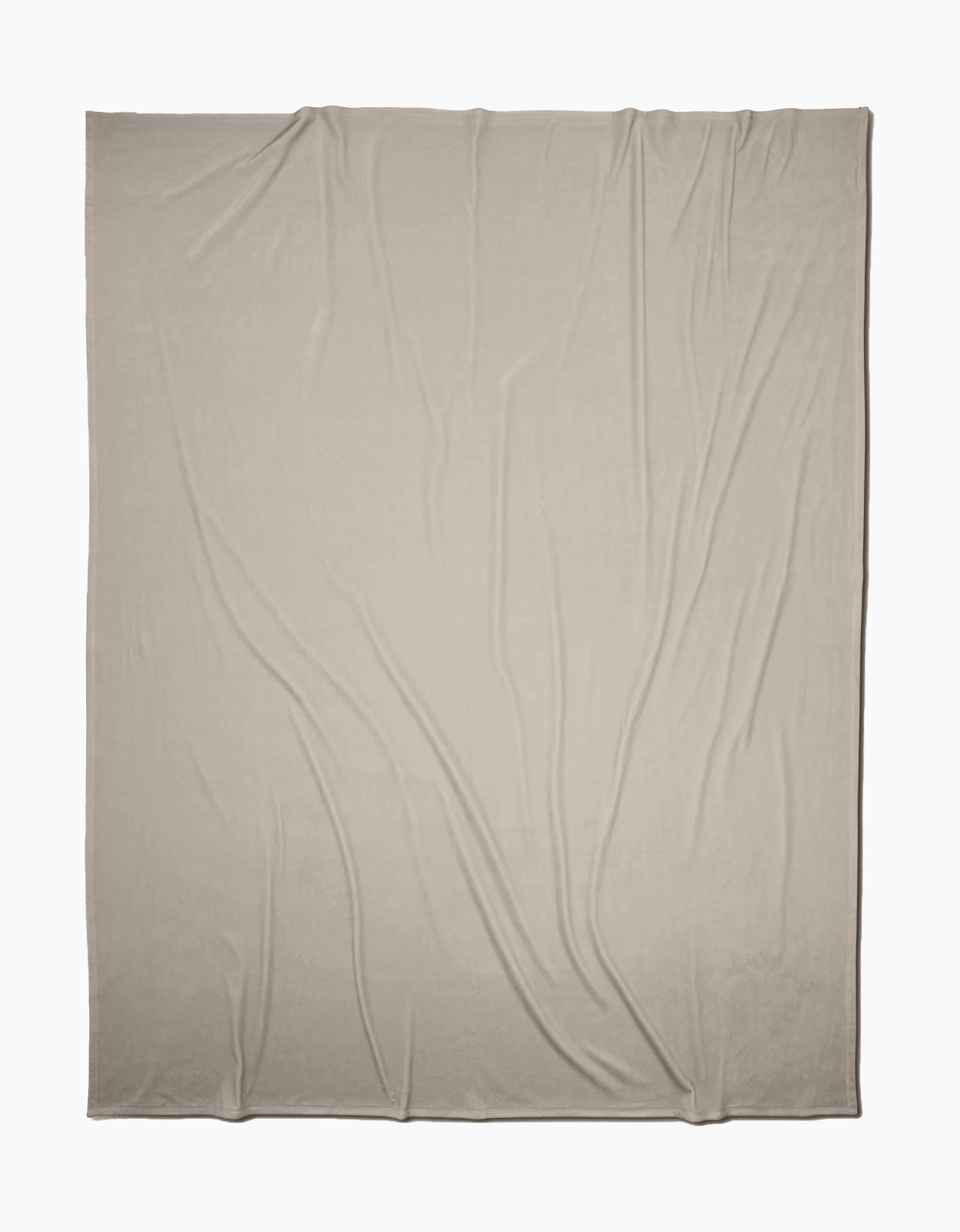 A GEOMETRY Desert Haze Butter Blanket, in light beige, is laid out flat with soft folds and wrinkles on a white background, highlighting its silky texture.