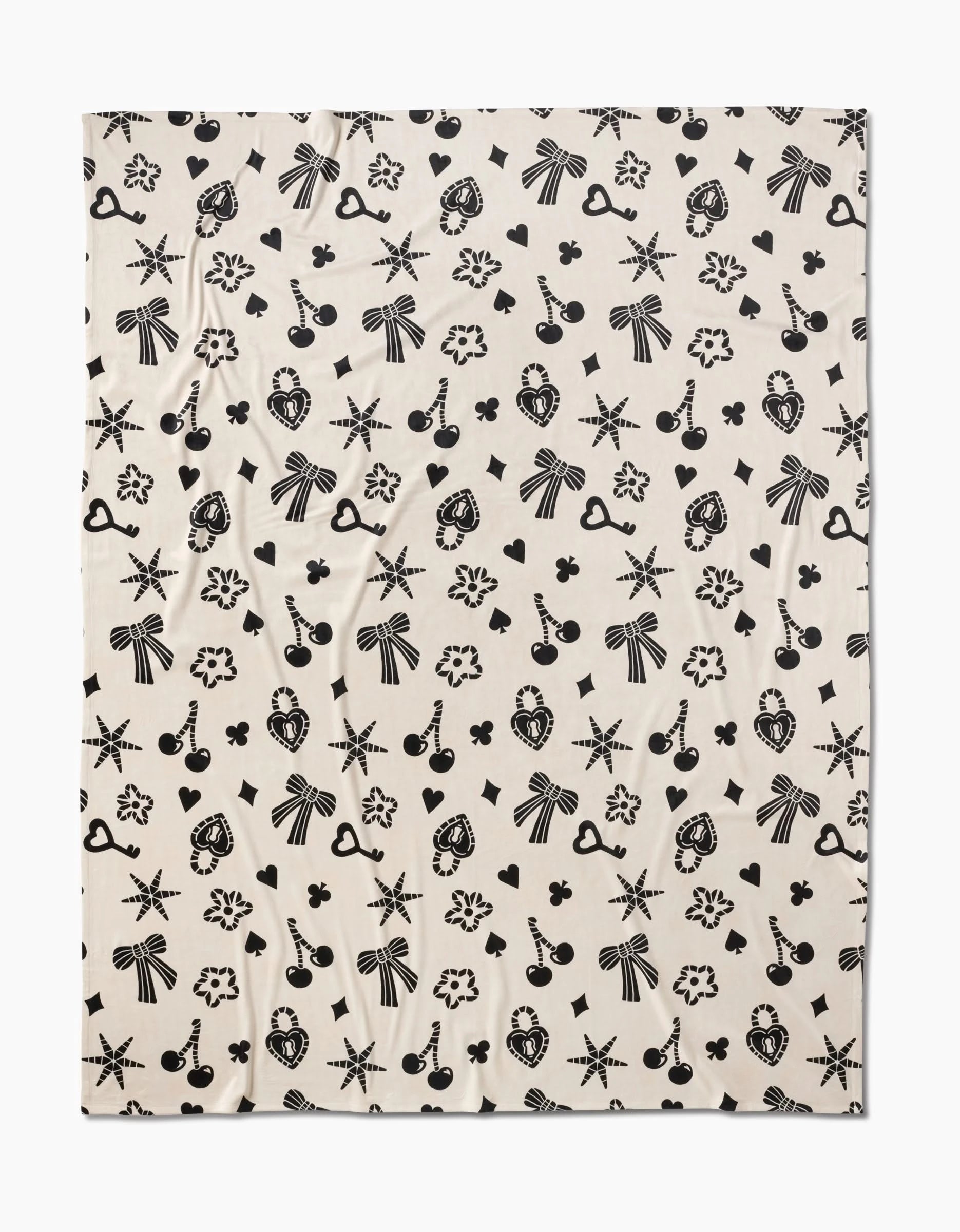 Heart Locket by Geometry is a cream-colored, silky-soft fabric adorned with evenly spaced black bows, starbursts, cameo profiles, hearts, keys, cherries, and flowers for a whimsical touch.