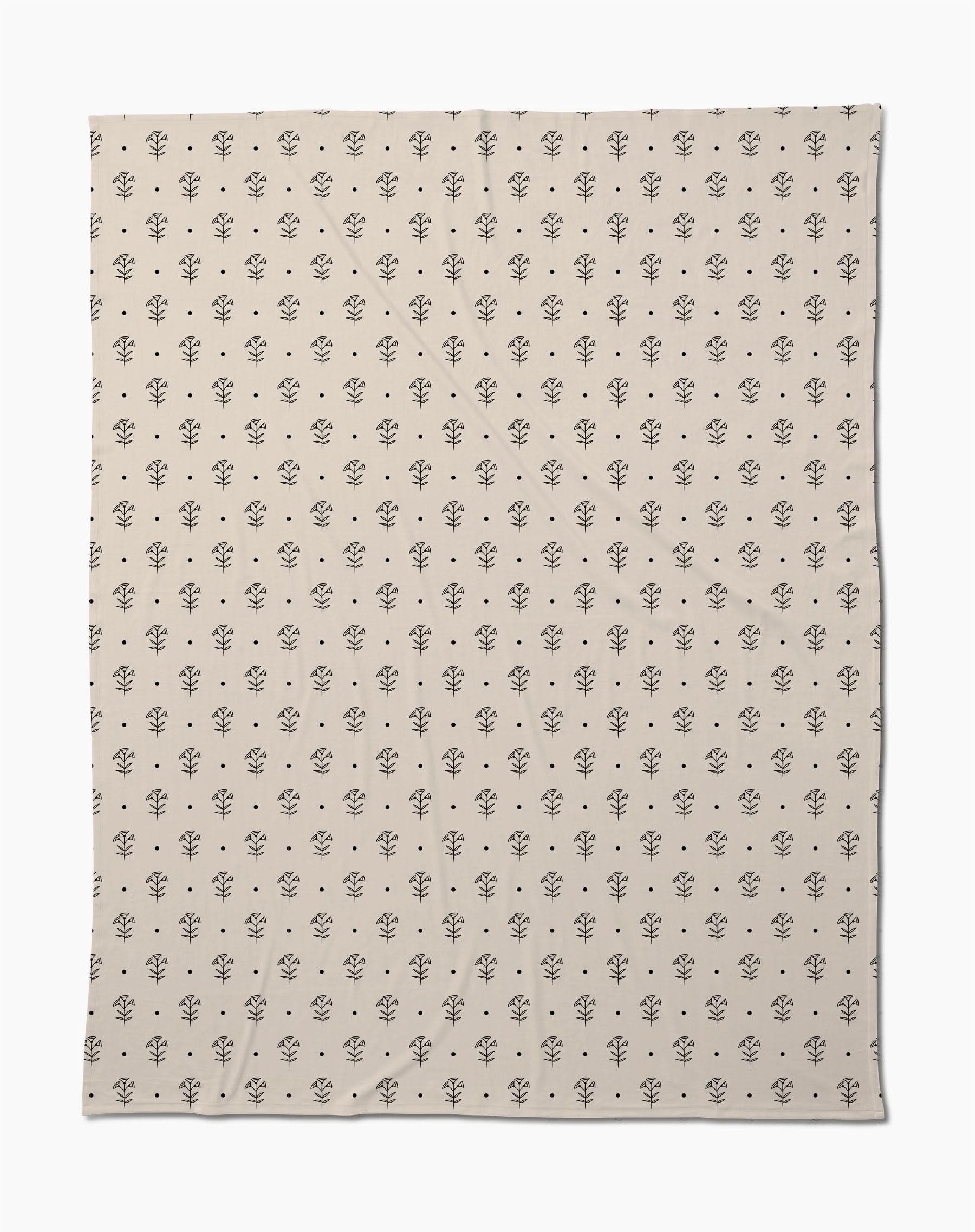The Inked Bloom by Cole Strem is an eco-friendly, beige blanket with a simple, repeating black floral motif. Made from recycled materials, it appears soft with subtle natural wrinkles.