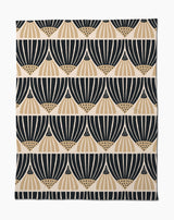 The Letitia Dark Butter Blanket by Amy MacCready features black and tan geometric fan patterns on white, arranged in horizontal rows. Made from eco-friendly recycled materials, it offers a modern, minimalist style.