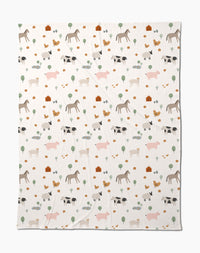 The Coit Creative Light Farm Animals blanket showcases a charming pattern of farm animals, trees, flowers, and barns on a white background. Made from eco-friendly recycled materials, its a cozy and conscious addition to your home.