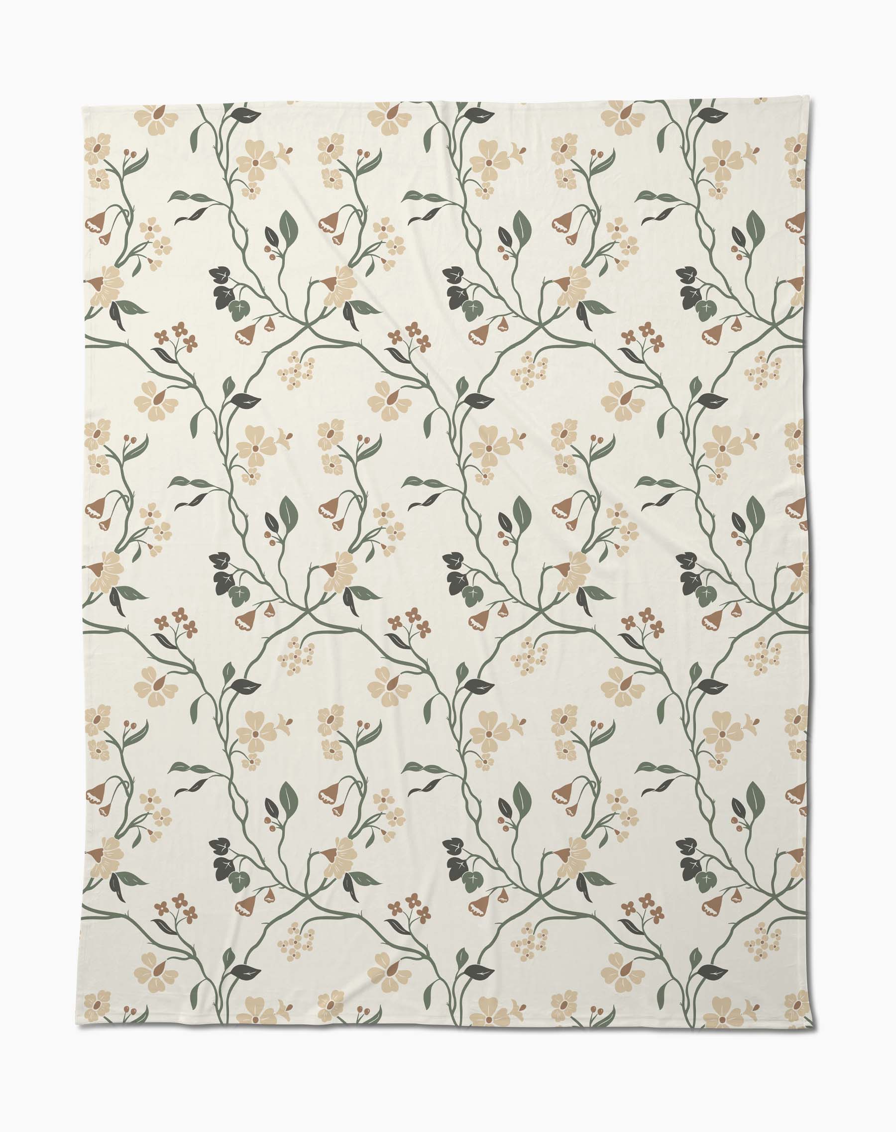 The Lunaria in Alabaster by Danelys Sidron is a cream-colored throw with green vines and beige, brown, and yellow flowers in a botanical pattern—crafted sustainably from recycled blankets.