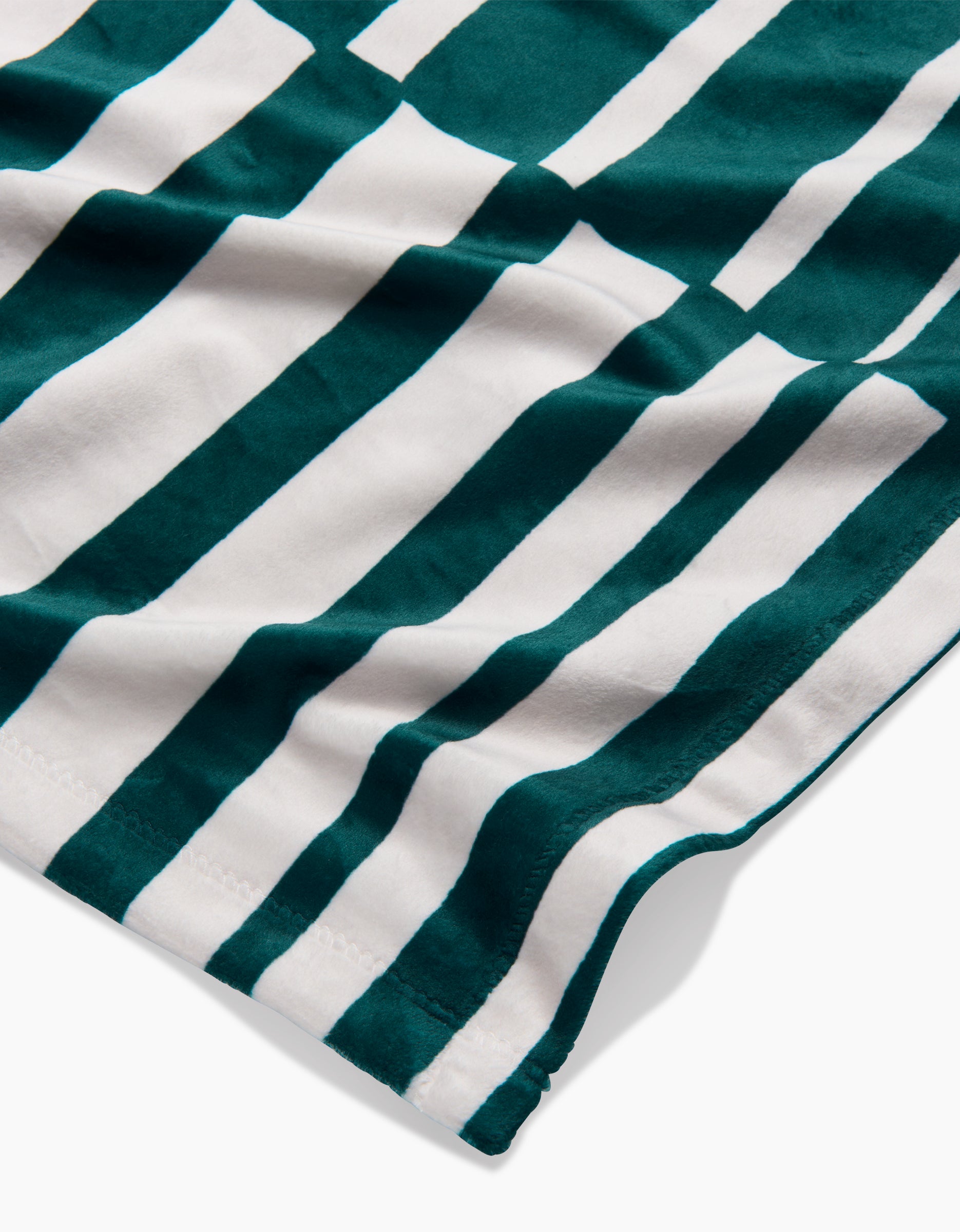 A close-up of Geometrys Verdelia fabric, showcasing alternating dark green and white vertical stripes with a subtly wavy, silky texture and visible edge stitching.