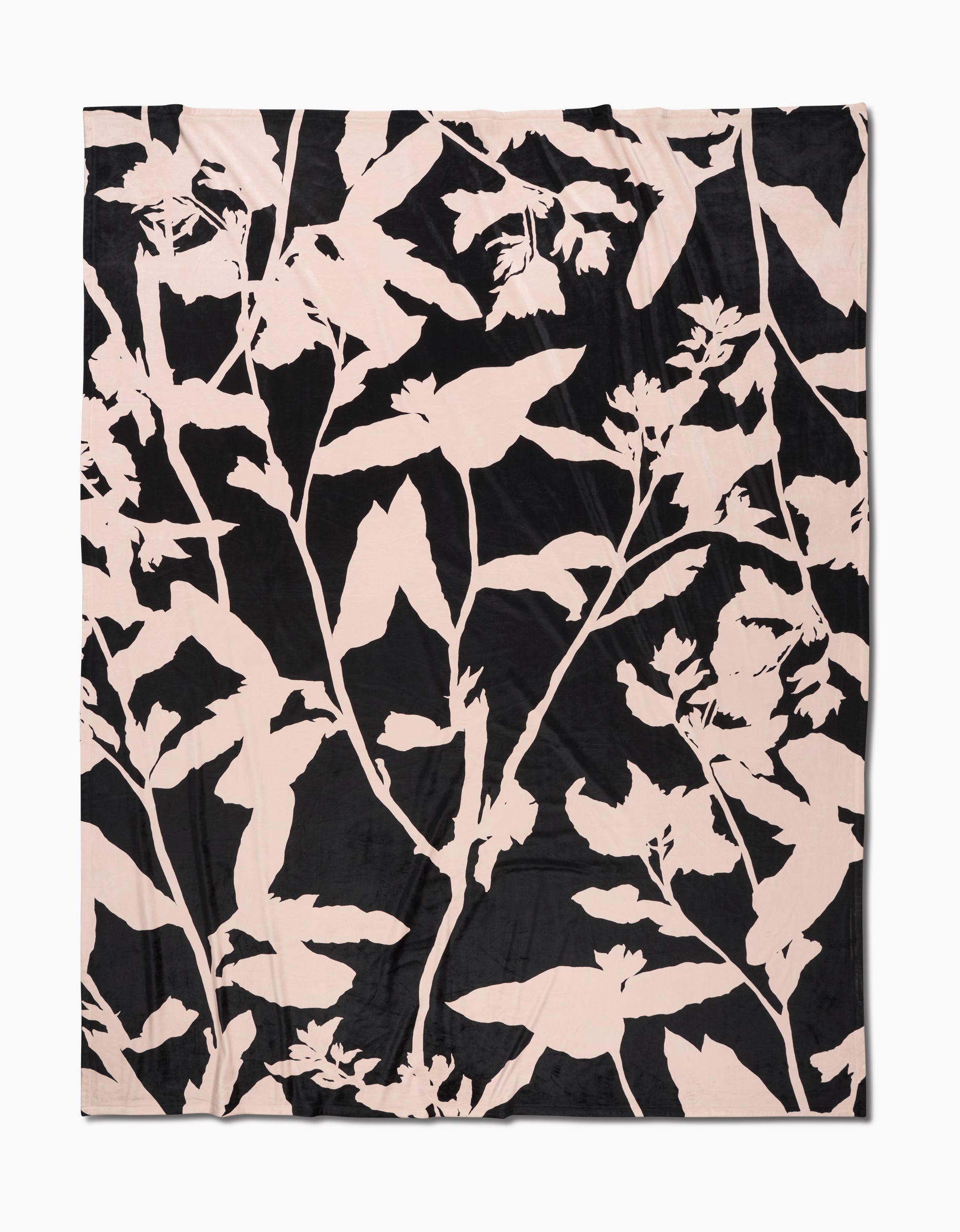 The Geometry Pam Butter Blanket features a bold, abstract botanical pattern with large pale pink leaf and stem shapes on a solid black background, crafted for silky softness.