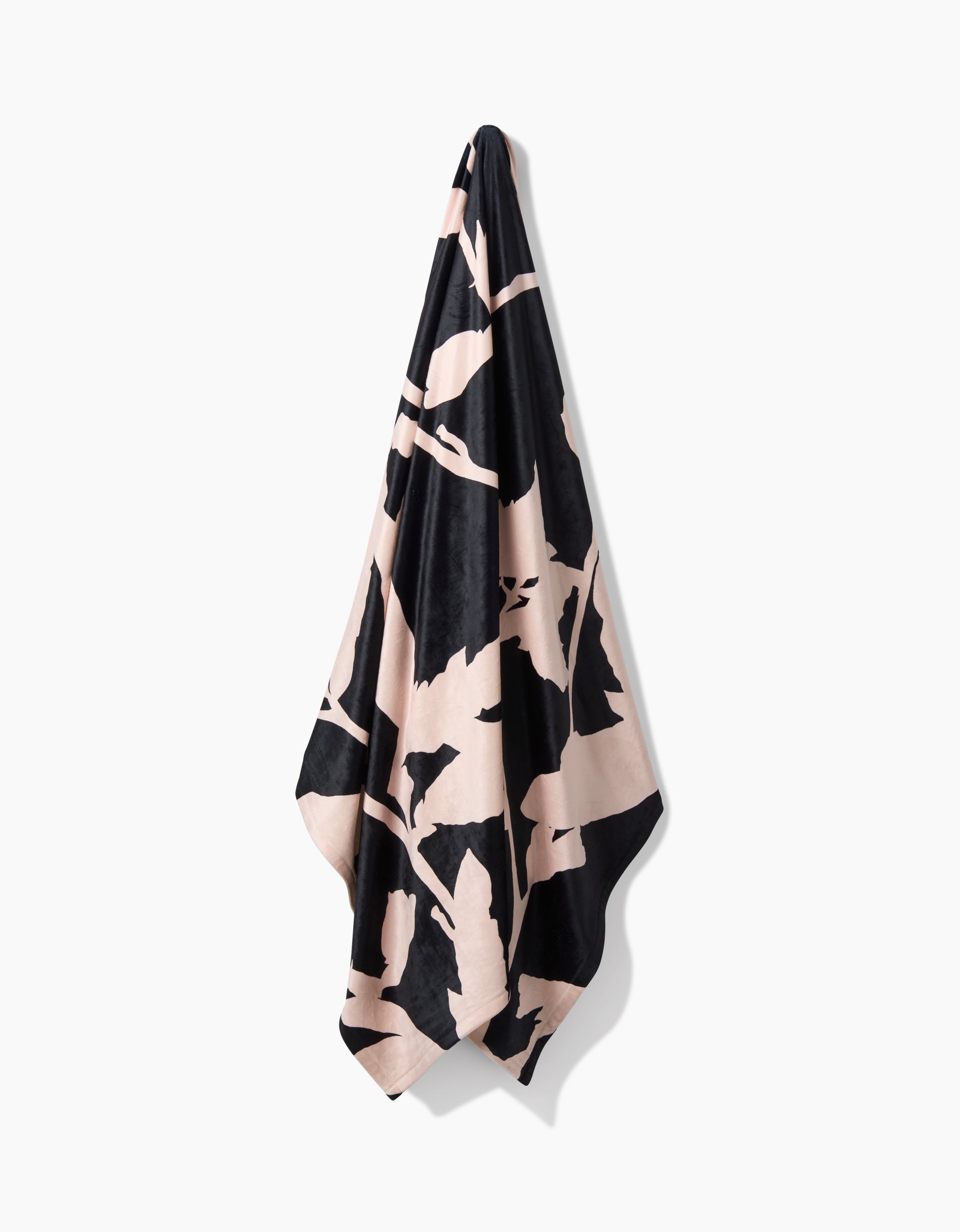 Pam, a black and beige patterned towel by Geometry made from recycled materials, hangs on a hook against a white background.
