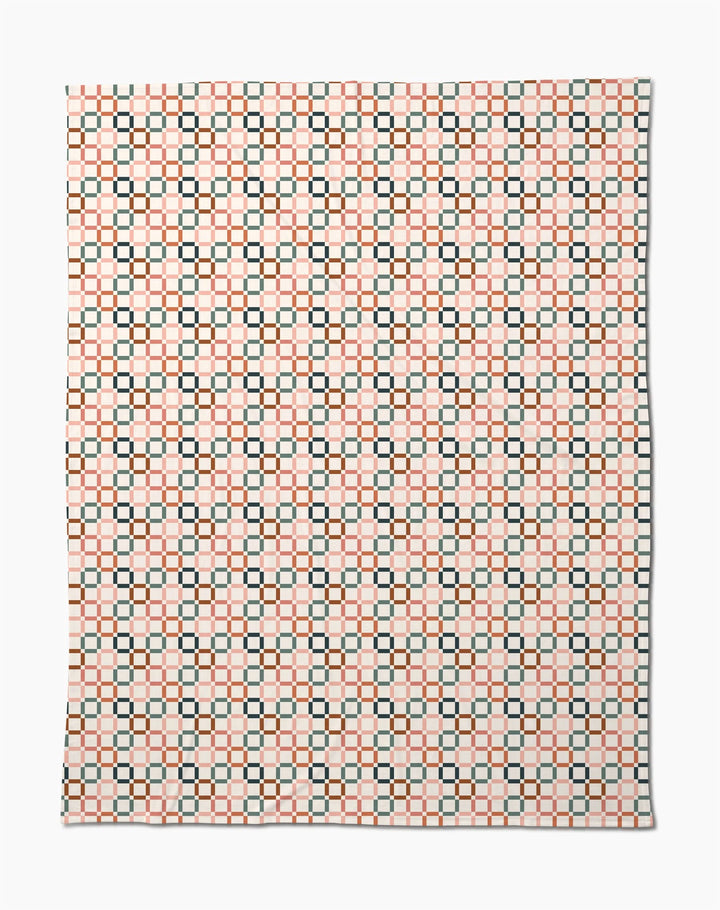 The Russet Crossroads Butter Blanket by Charlie Rowan Designs features a symmetrical geometric pattern of black squares and orange lines on white, crafted from recycled materials for an eco-friendly, stylish look.