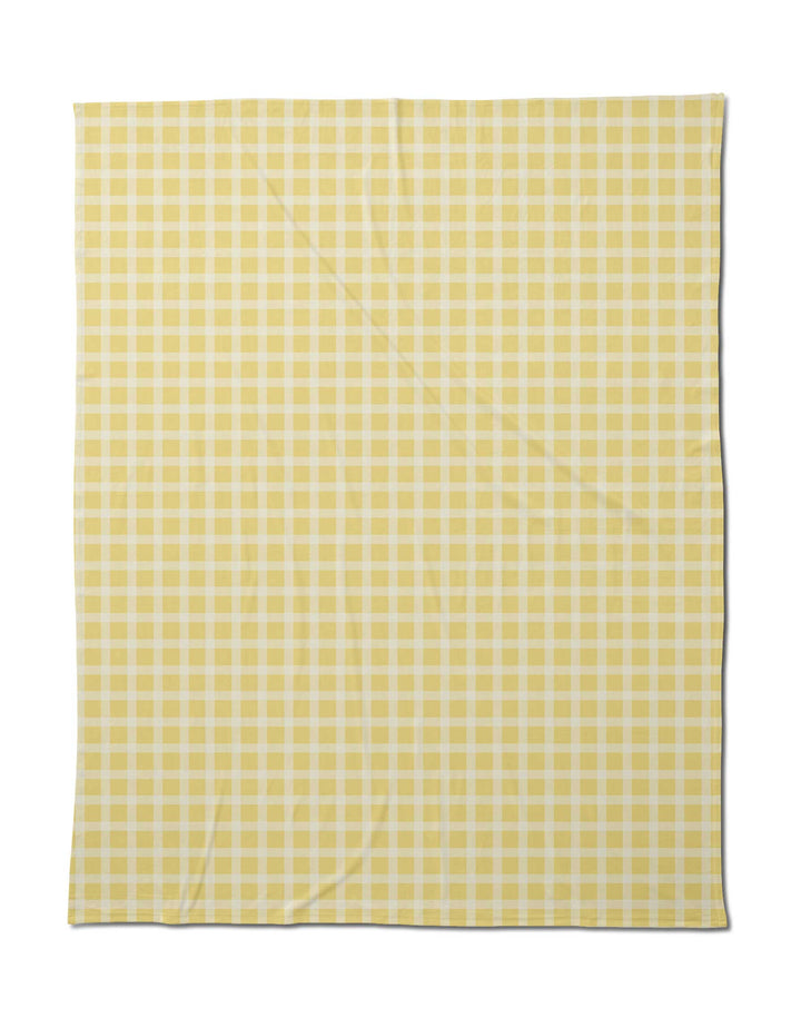 The Geometry Sunspread is a rectangular blanket with a yellow and white gingham check pattern, laid flat with subtle creases, providing silky softness for cozy comfort.
