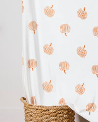 A Geometry Tales From the Patch Butter Blanket, featuring simple orange pumpkin illustrations, is draped over a woven basket.