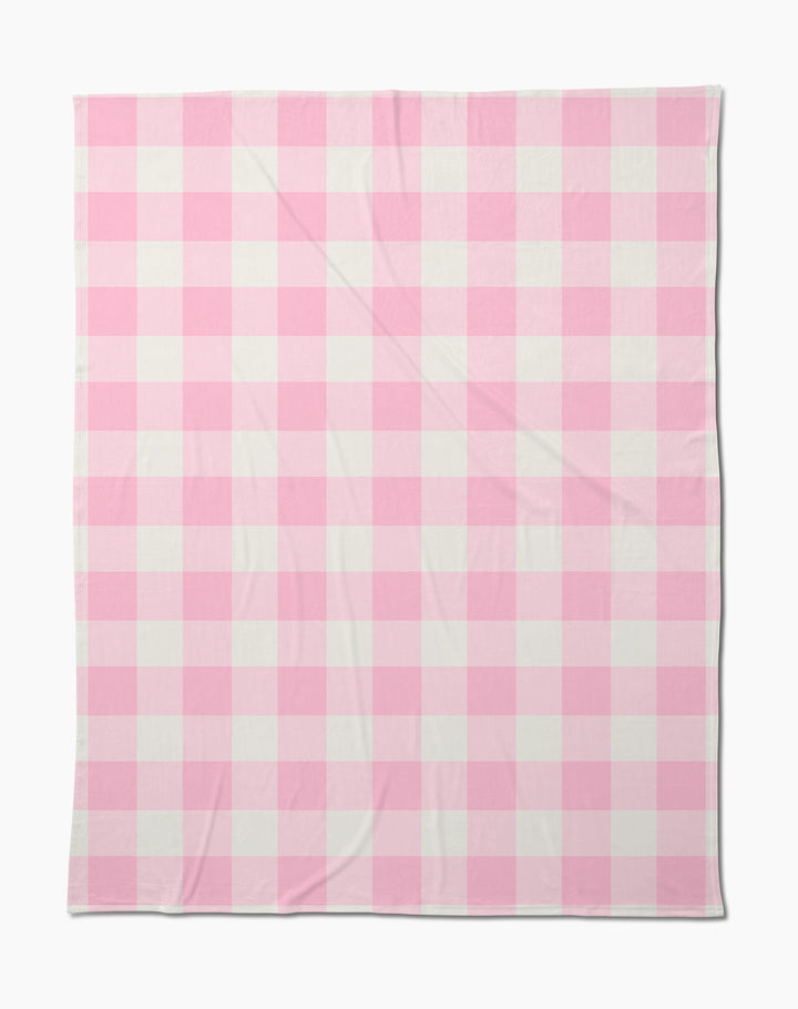 The Geometry Val Butter Blanket showcases a pink and white gingham checkered pattern, laid flat against a white background.