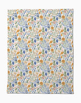 Wildflower Vine Blush by Danelys Sidron is a silky soft fabric with a vibrant floral pattern of small orange, blue, pink, and yellow flowers and green leaves densely scattered on a white background.