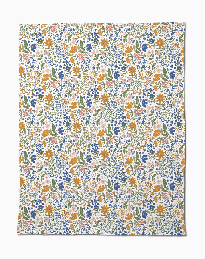 Wildflower Vine Blush by Danelys Sidron is a silky soft fabric with a vibrant floral pattern of small orange, blue, pink, and yellow flowers and green leaves densely scattered on a white background.