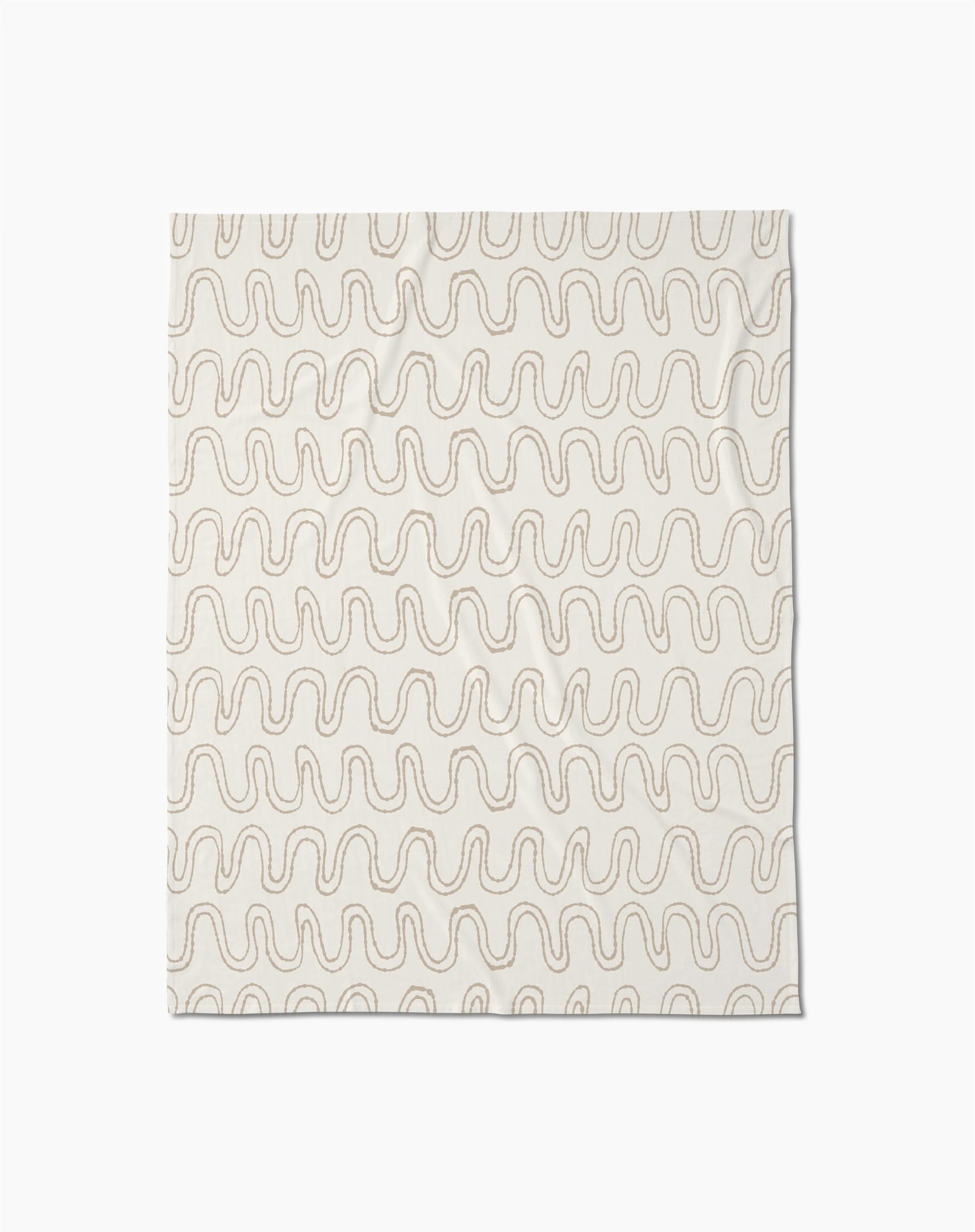 The Abstract Squiggles throw blanket by Geometry is crafted from recycled blankets for comfort and sustainability, featuring a soft cream color with evenly spaced wavy beige lines in a repeating pattern, displayed flat against a white background.