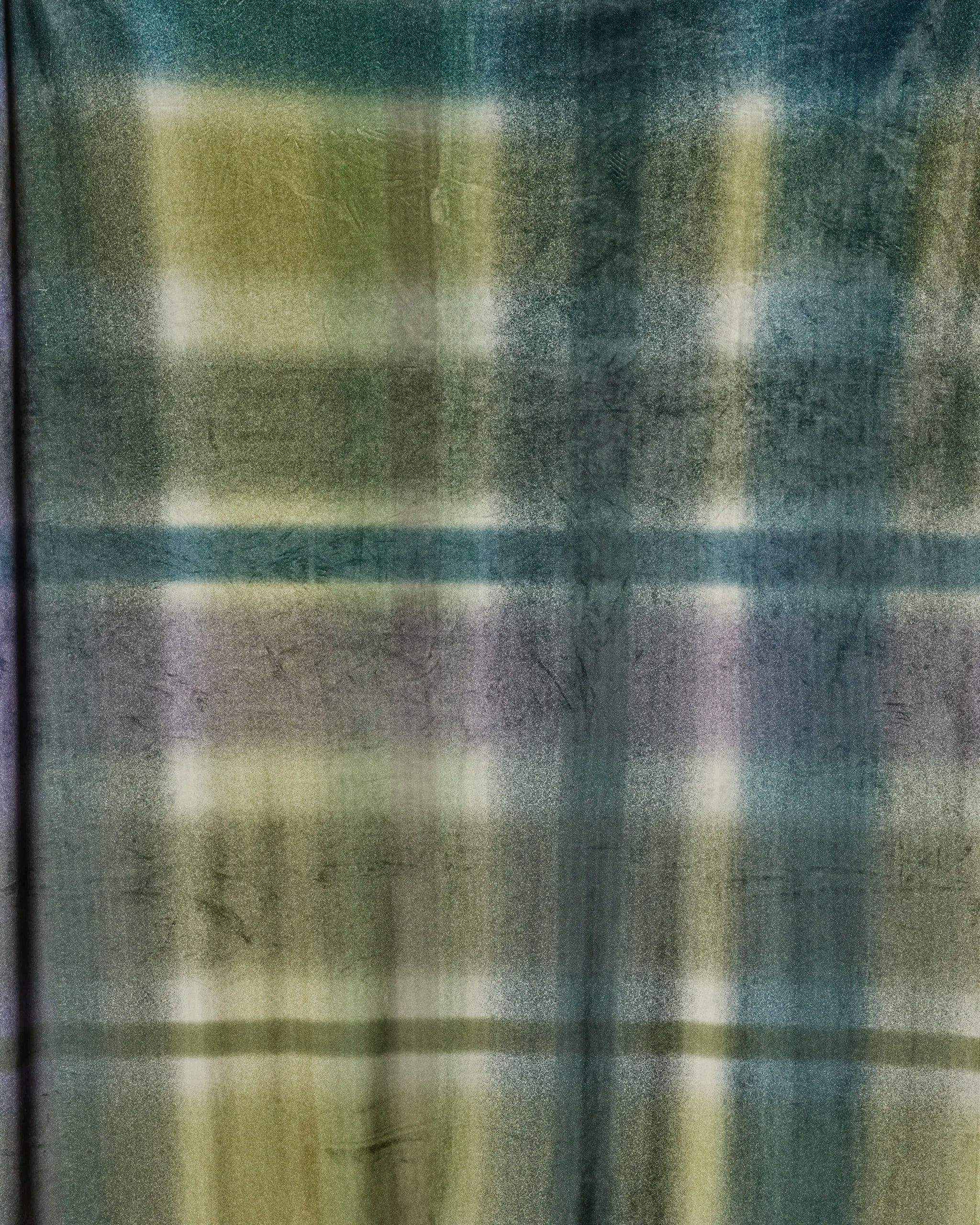 The Bracken Butter Blanket by Geometry features a soft, fuzzy feel with a blurred plaid pattern in green, yellow, blue, and purple for a gradient watercolor effect—an eco-friendly cozy recycled blanket for any space.