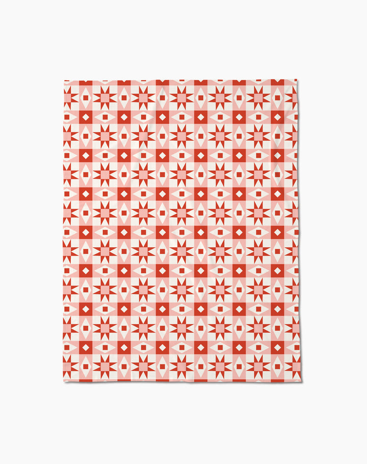 The Chalet Butter Blanket by Charlie Rowan Designs features a geometric pattern of red and white squares, diamonds, and stars in a grid on white—perfect as a soft throw blanket.