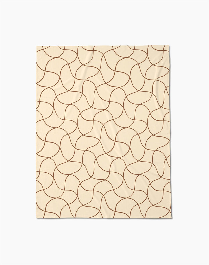 The Geometry Clarity throw blanket is beige and rectangular, featuring a soft texture with an abstract pattern of curving brown lines that form a repeating, interconnected design across the surface.