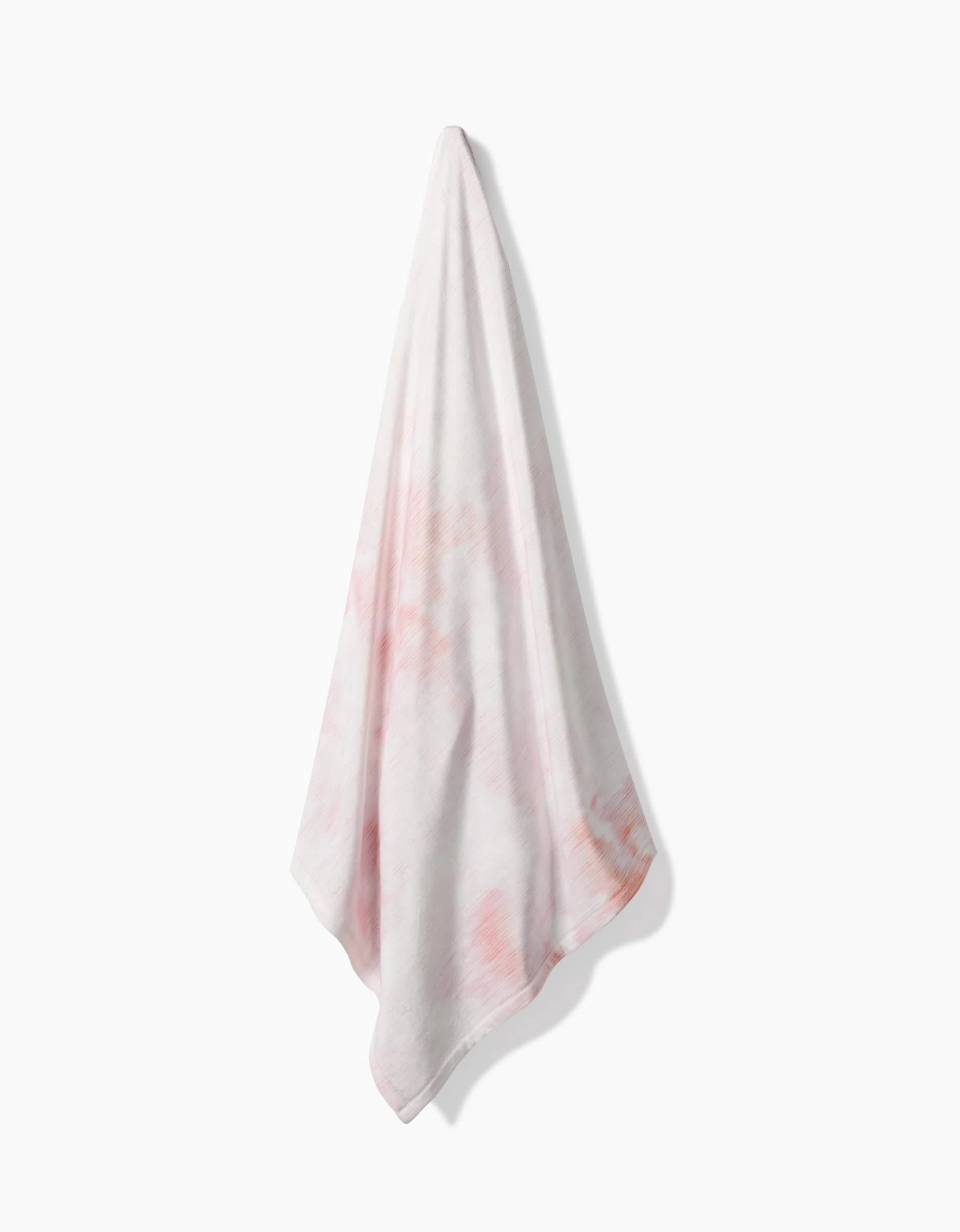 The In the Clouds towel by Geometry, featuring light pink patterns on white and made from recycled materials, hangs from a single point against a plain white background with a soft shadow.