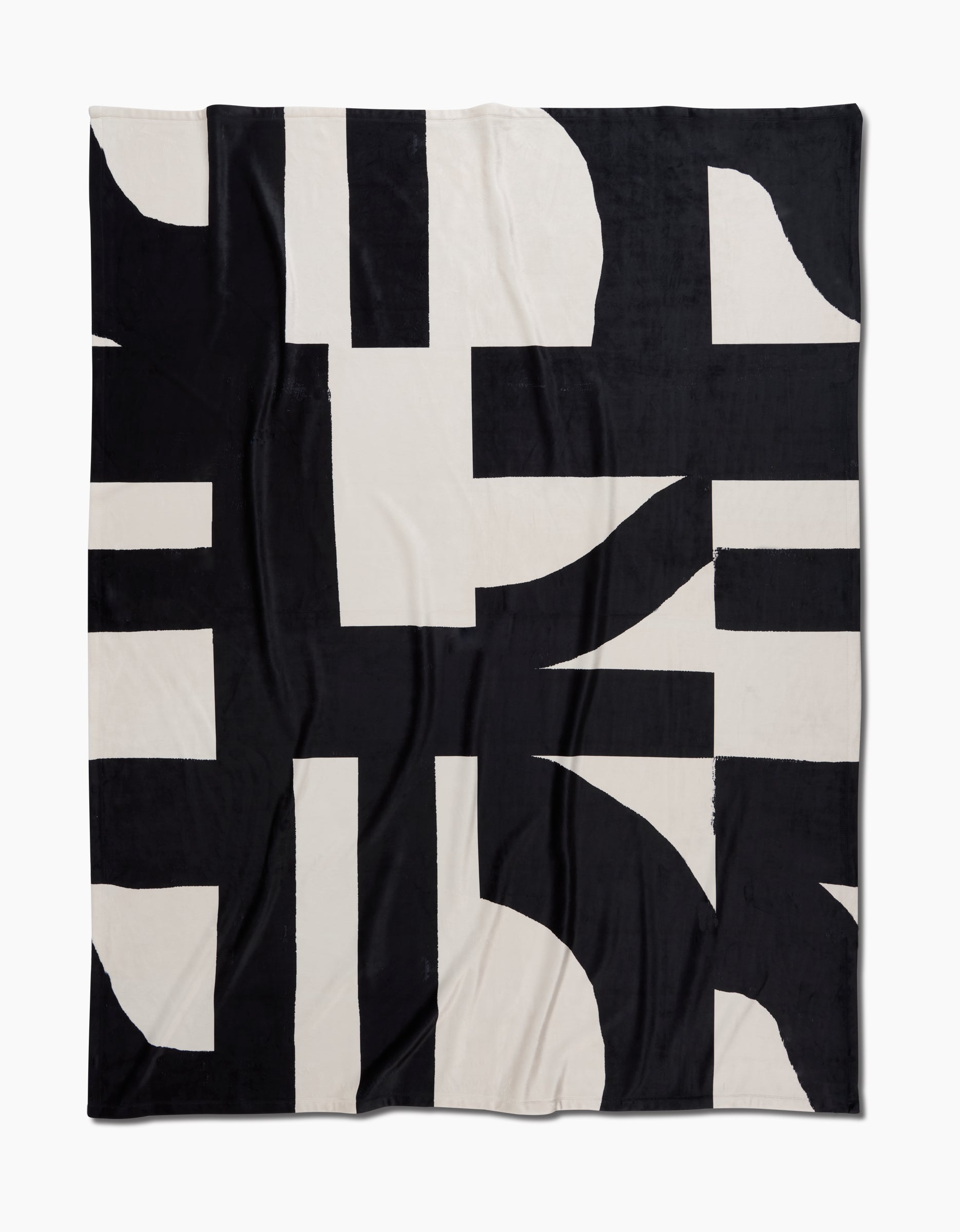 Geometry’s Lined Square Butter Blanket features a bold black and off-white abstract geometric pattern with intersecting shapes and thick lines. Made from post-consumer recycled materials, it offers silky softness and sustainable comfort.