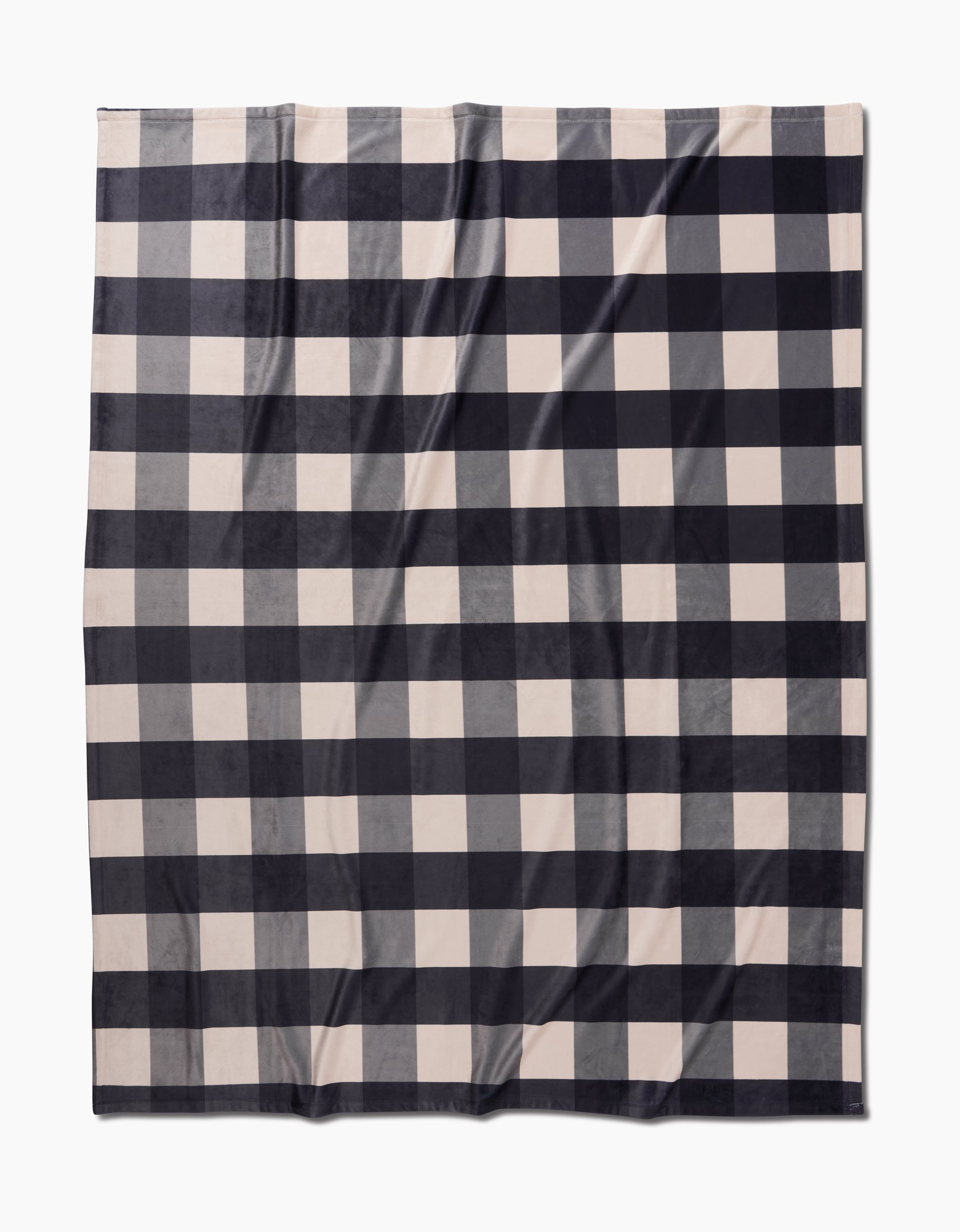 The Geometry Snowy Gingham is a rectangular Butter Blanket with a black and white buffalo plaid pattern, crafted for silky softness and shown laid flat on a white background.