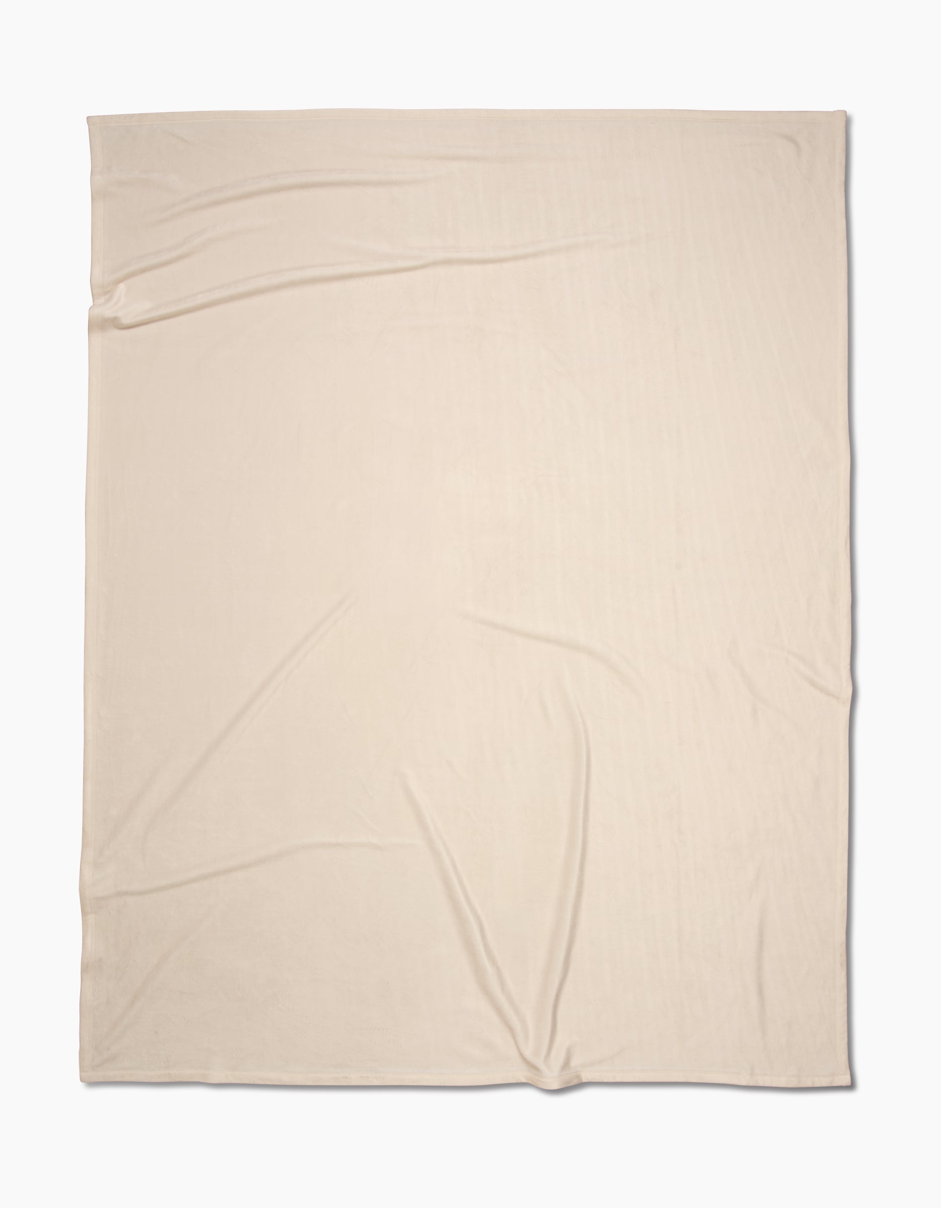 A beige, rectangular Soft Glow blanket by GEOMETRY, crafted from eco-friendly recycled materials, lays flat with slight wrinkles on a white background.