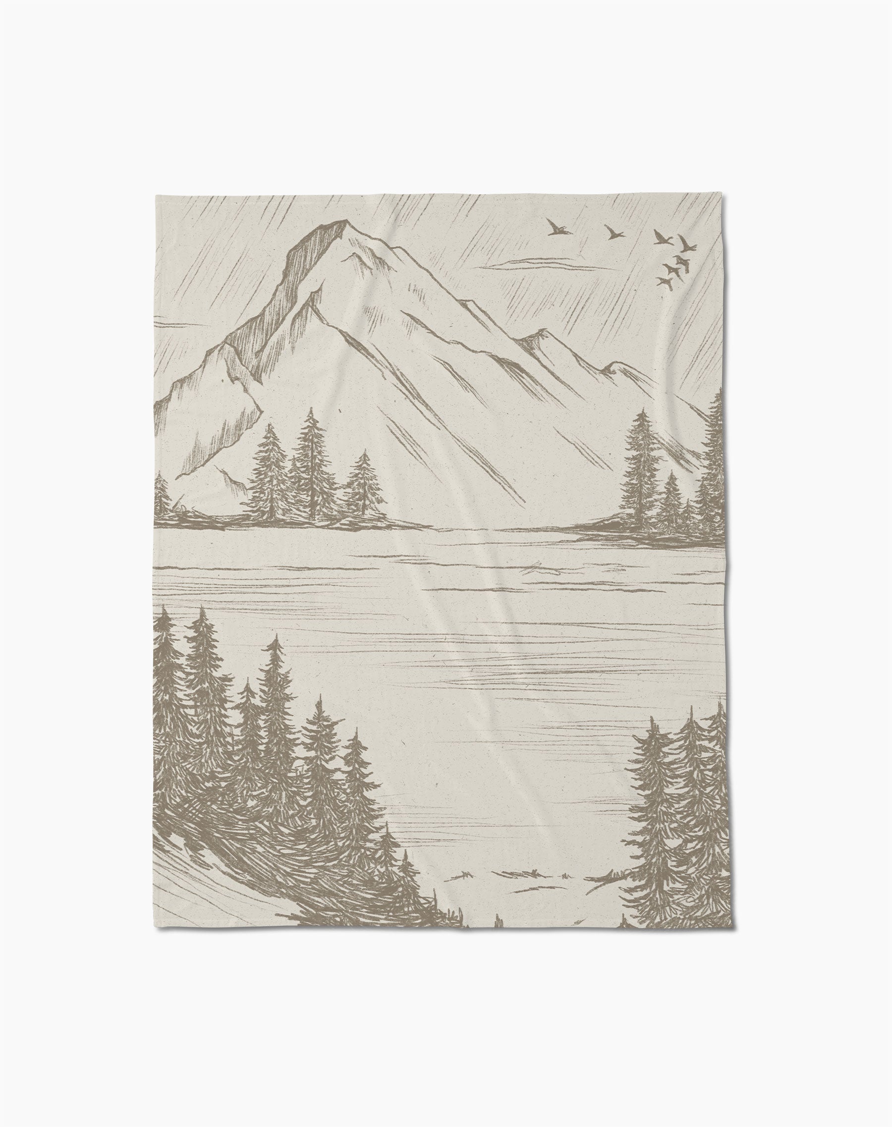 The Geometry Stillpine throw blanket, in textured beige, displays a detailed mountain landscape with pine trees, a lake, and birds in flight.