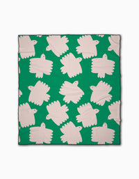 The Birds beach blanket by Jennifer Bouron is green, made from recycled materials, and displays stylized white birds in a repeating, minimal pattern across its quick-drying surface.