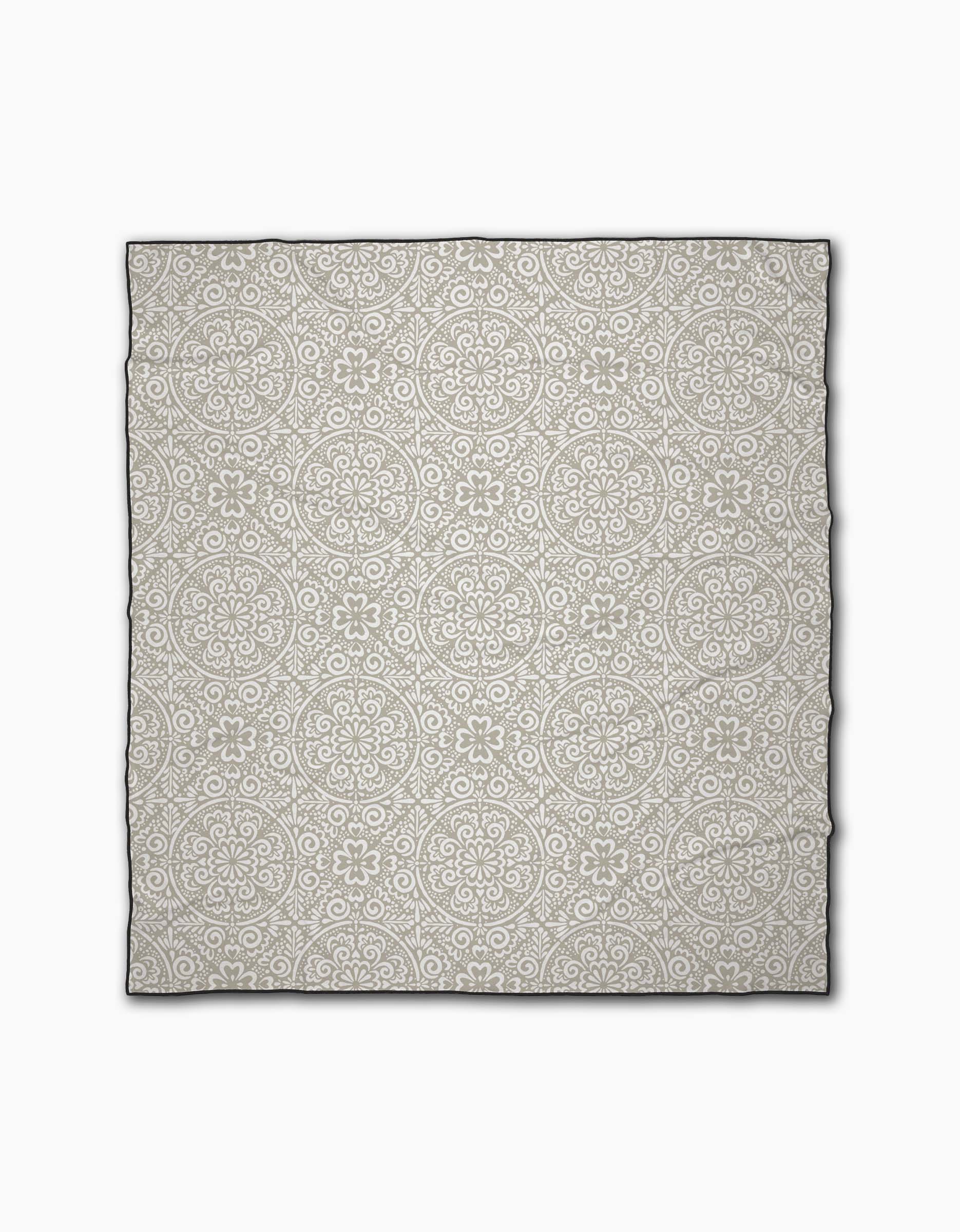 The Boho Medallion beach blanket by Kris Ruff features a light gray background with a white floral and geometric circular pattern. Crafted from quick-drying recycled materials, it delivers comfort and eco-friendly style.