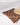 A straw hat and pink sunglasses rest on a folded Geometry Caramel Kiln Micro-loop Beach Blanket, showcasing its brown and black pattern against a crisp white background.