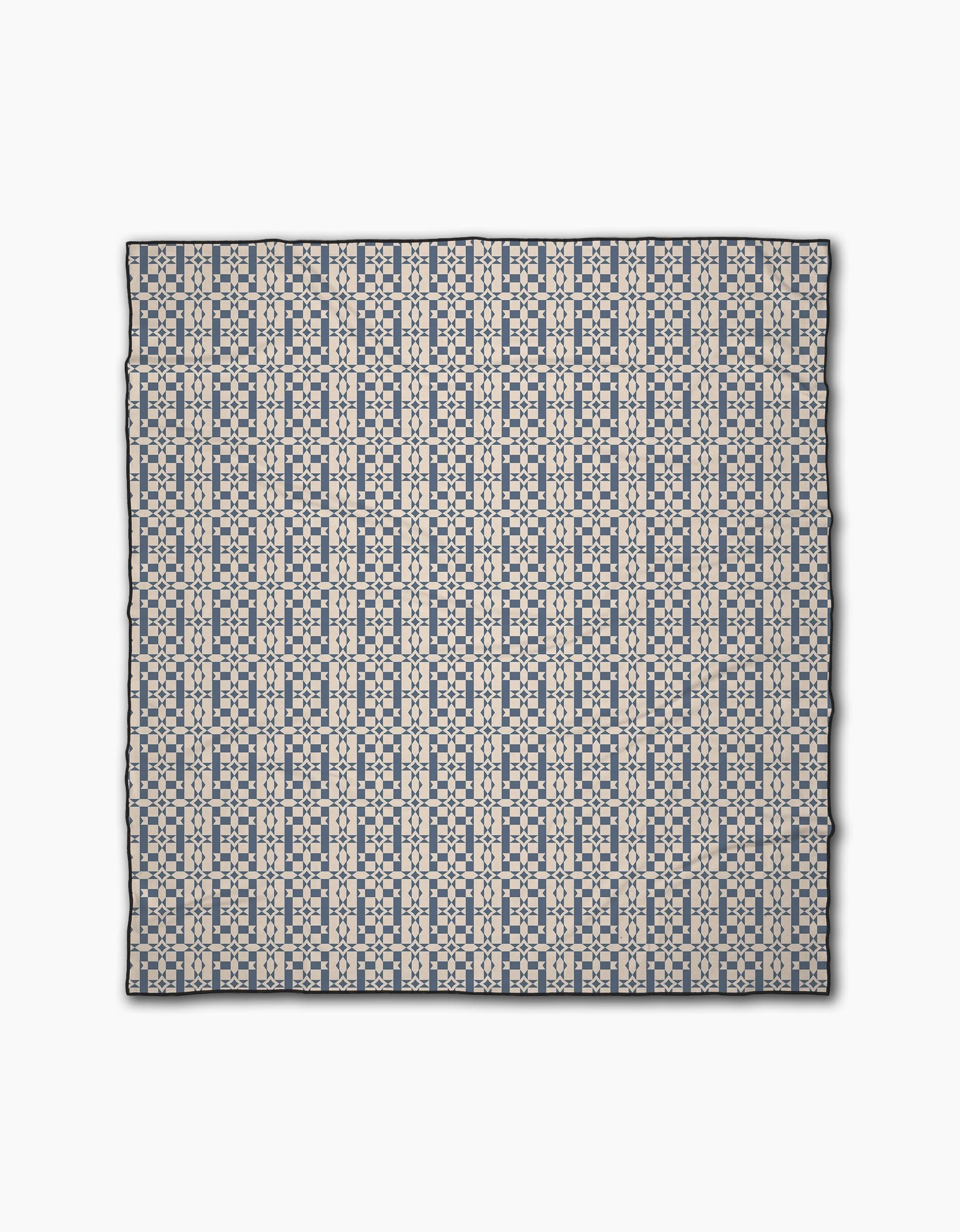 The Intermission Blue scarf by Geometry features a repeating geometric pattern in navy and light beige on white, made from recycled materials. Symmetrical lines and shapes add style as it lays flat on a white surface.