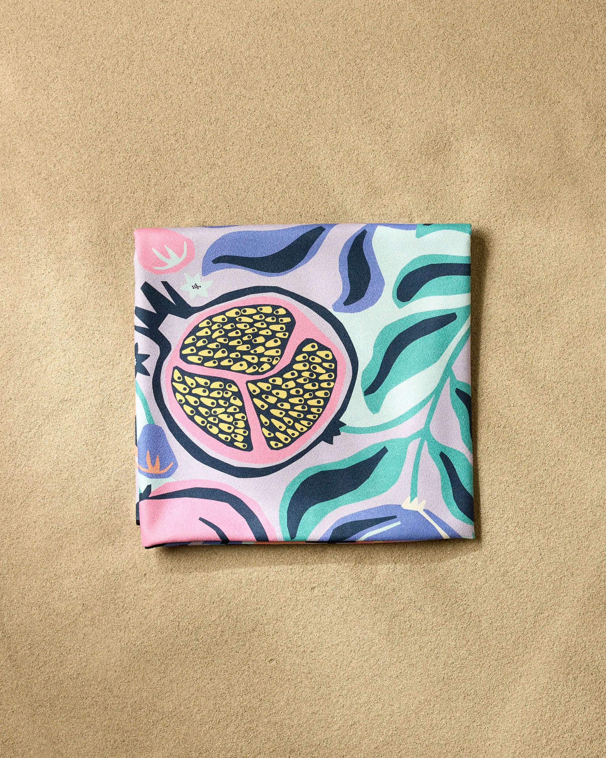 The Lucky Pomegranate beach blanket by Masha Volnova features a colorful abstract pomegranate and green leaves design. Made from quick-drying, recycled materials, it combines eco-friendly style with everyday convenience.